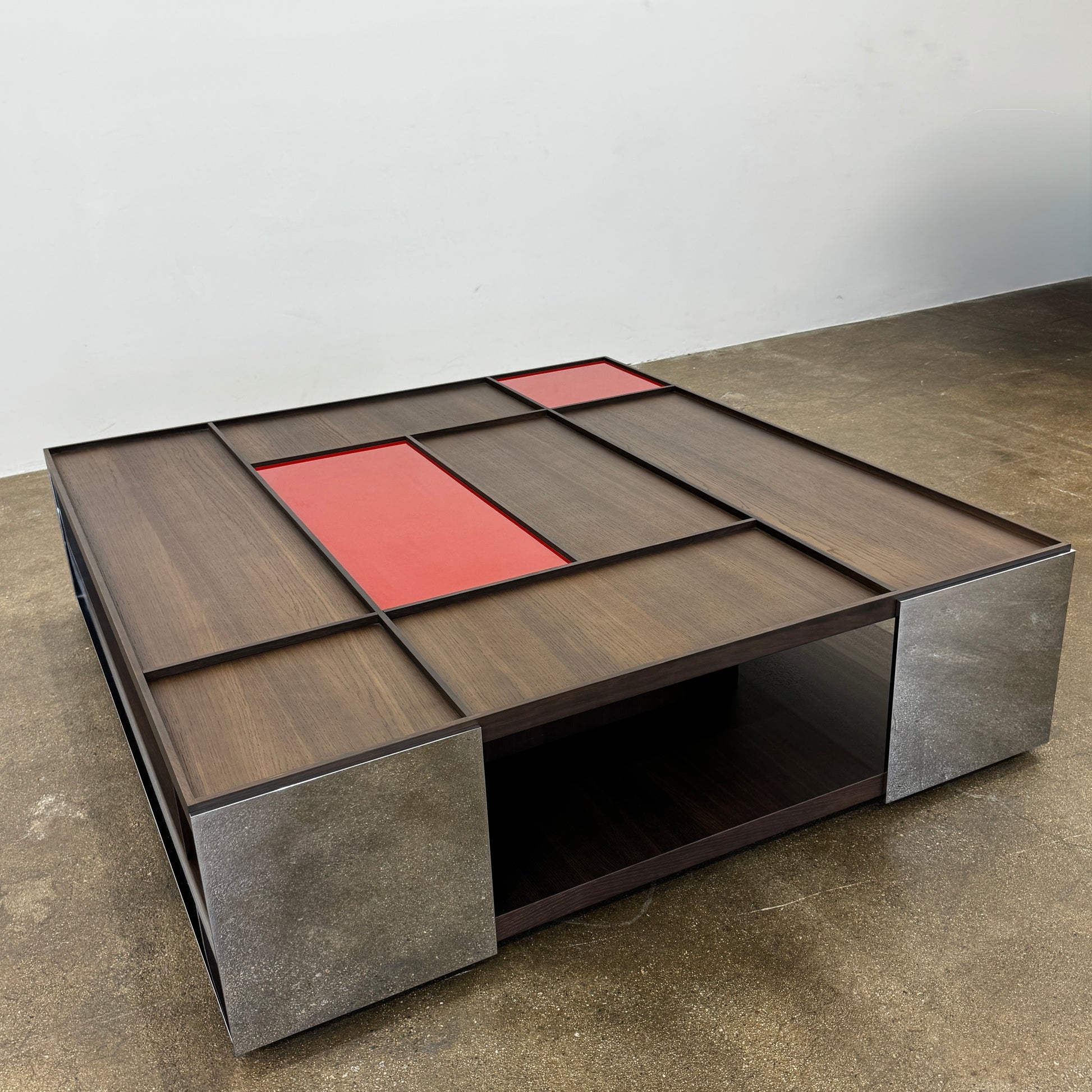 A modern square coffee table by B&B Italia, the Surface Coffee Table features wood, concrete-like panels, and two red rectangular accents—ideal for admirers of geometric designer furniture.