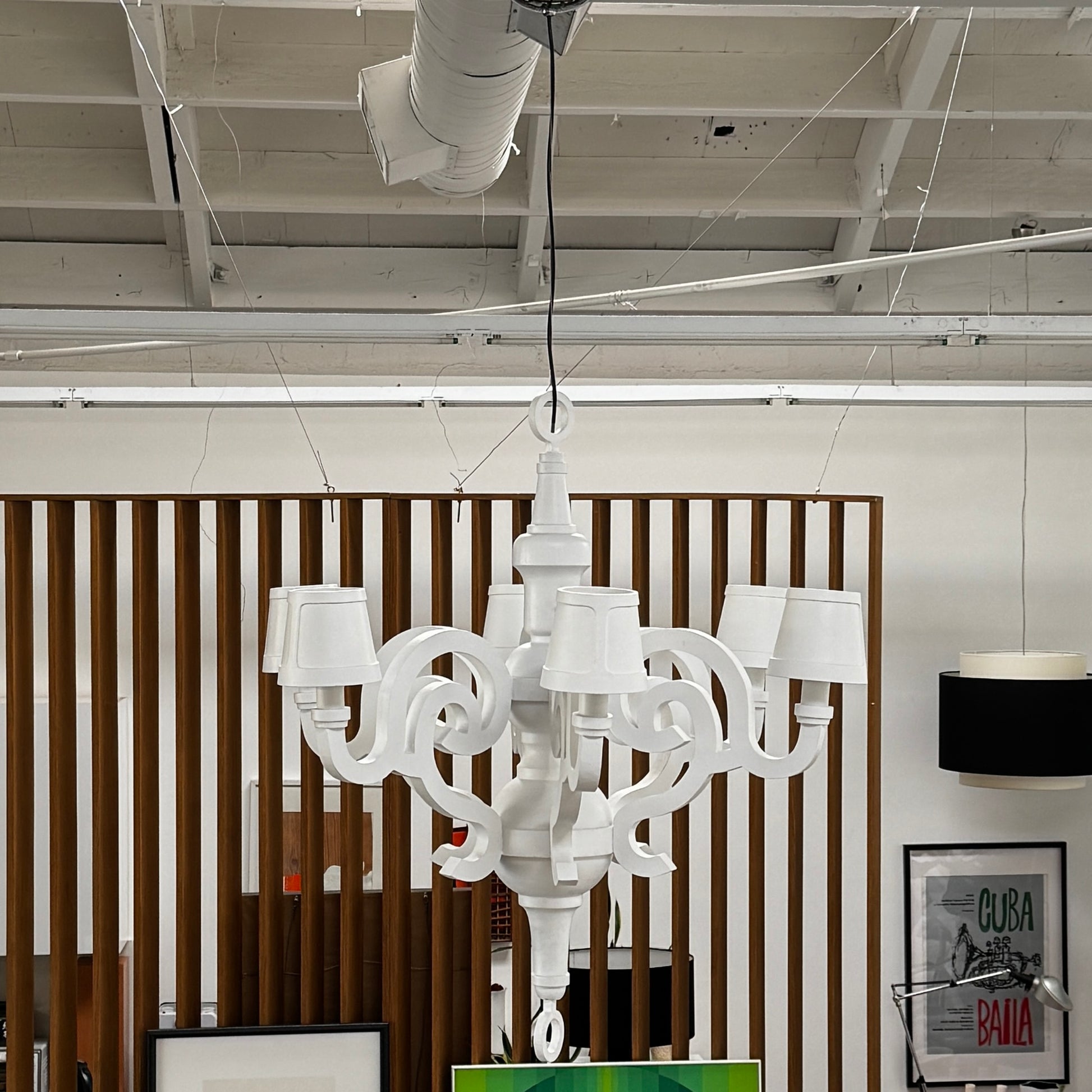 A white Moooi Paper Chandelier by Modern Resale with six arms and lampshades hangs from the ceiling on a black cord, serving as a striking 6 Light Chandelier centerpiece against a plain background.