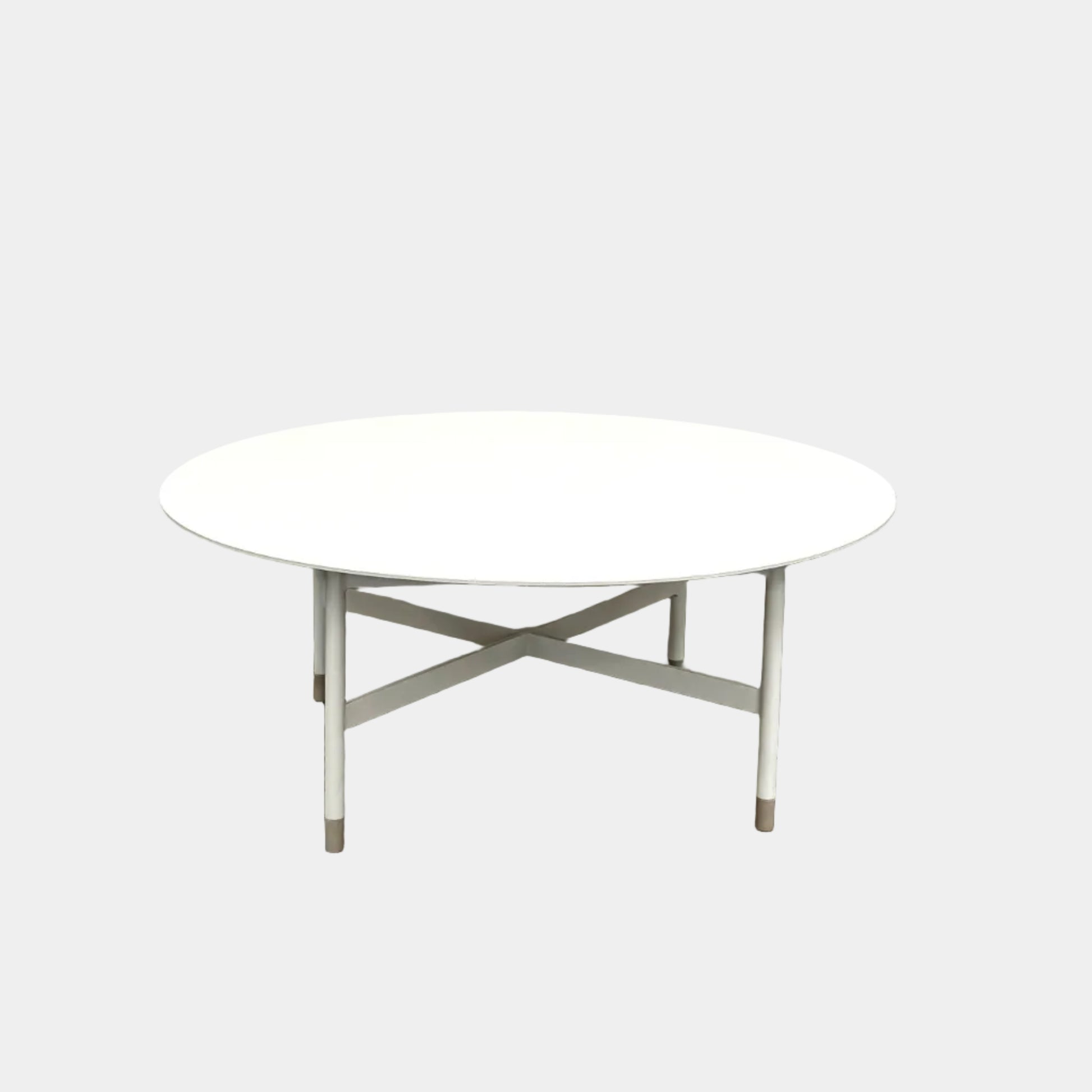 The MillerKnoll Sommer Outdoor Coffee Table for DWR is a round, white table with four legs and an X-shaped base, ideal for minimalist outdoor spaces. Brand: MillerKnoll. Set against a plain white background.