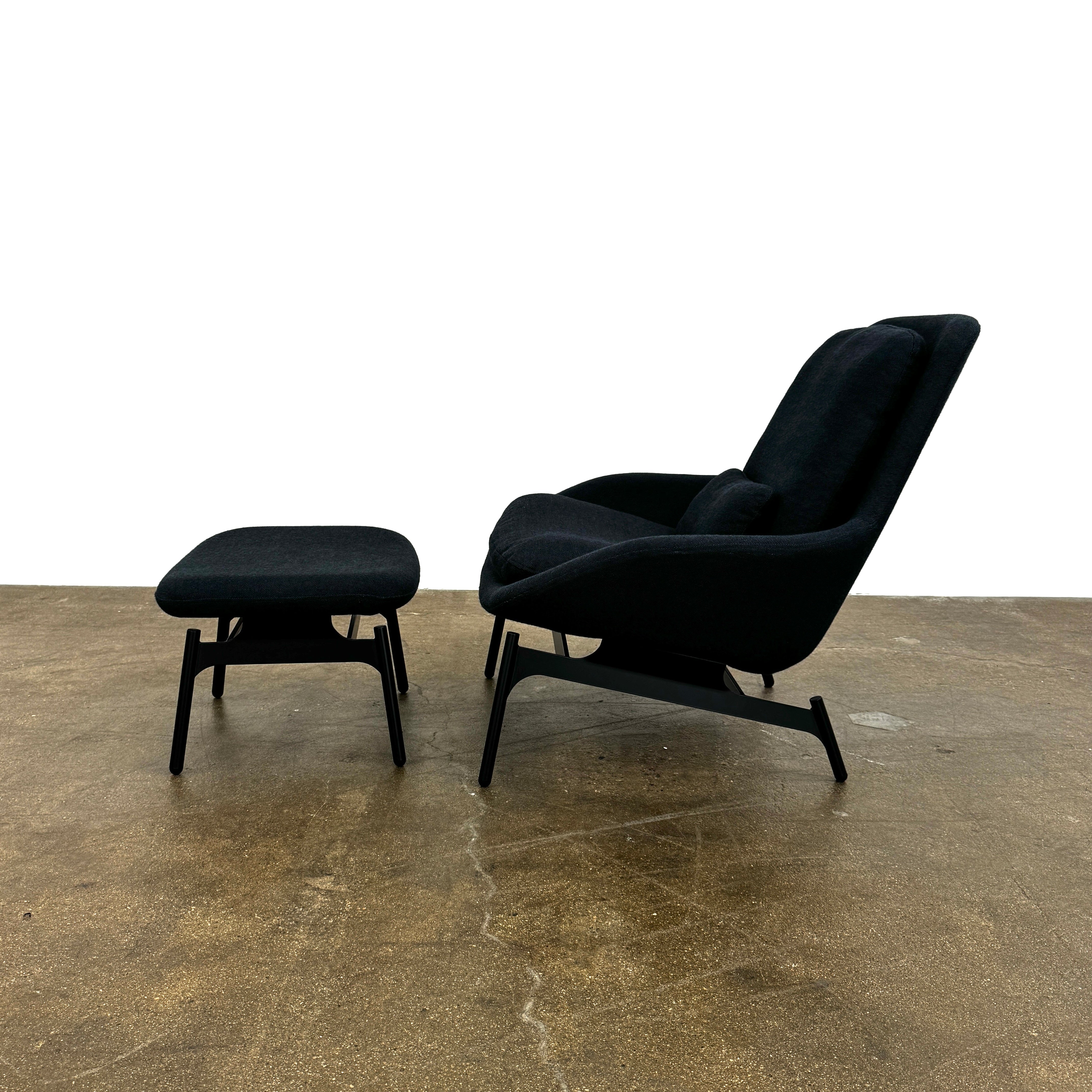 A Bludot Field Chair & Ottoman by Blu Dot, in modern black, is placed on a brown concrete floor with a white background.