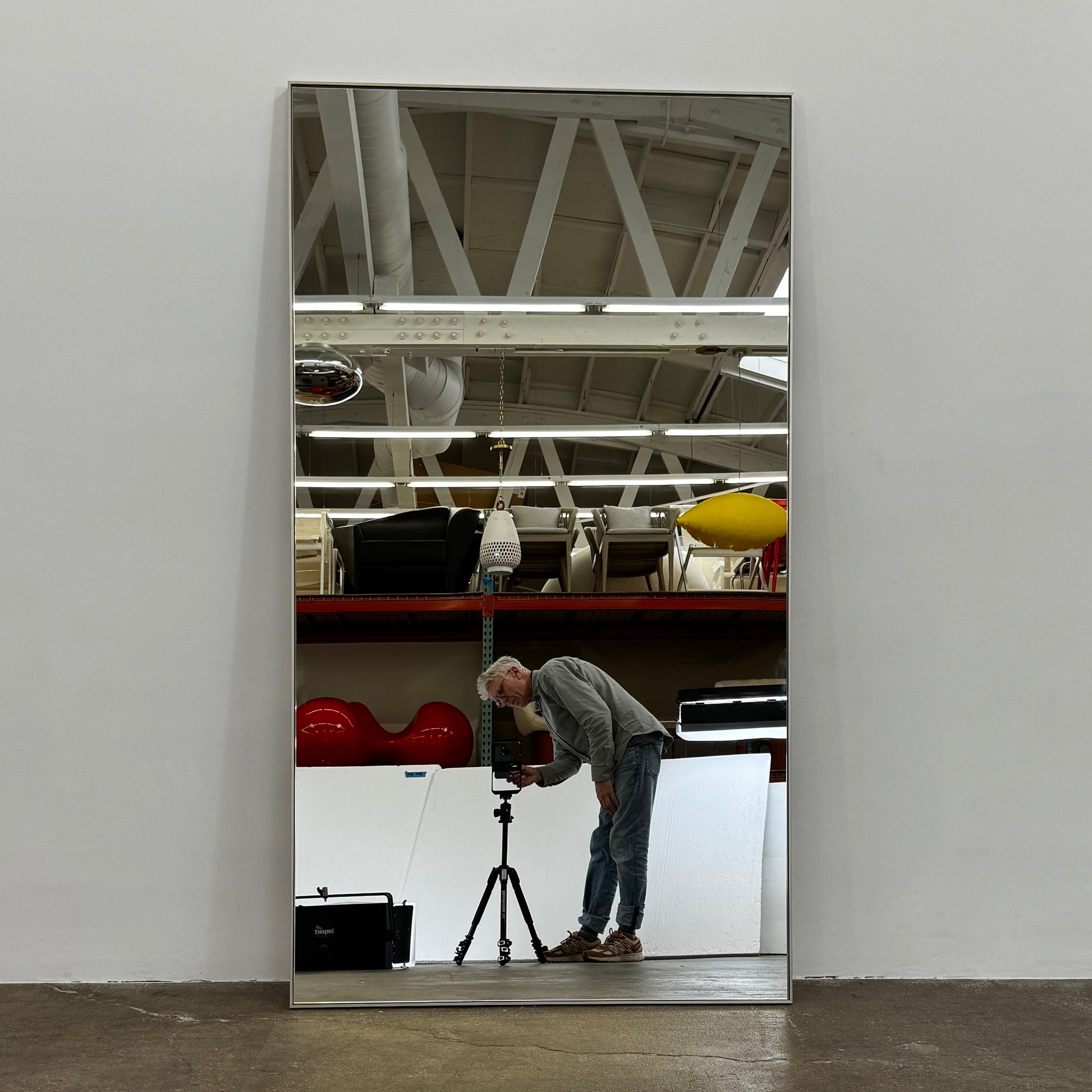 The DWR Mondrian Wall Hanging Mirror (44" x 80") by DWR features a sleek, minimalist rectangular design with a thin, dark frame and stands upright against a plain white backdrop for a modern look.