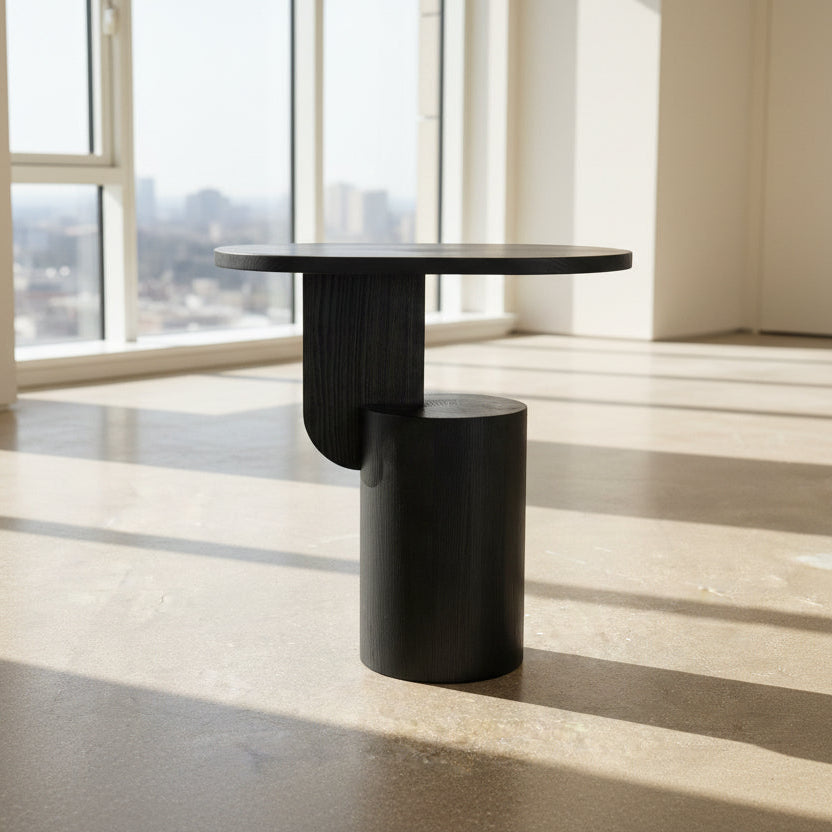 The Ferm Living Insert Side Table by Ferm Living features an oval dark wood top with a pedestal base, creating a striking accent on concrete floors and showcasing subtle Scandinavian design.
