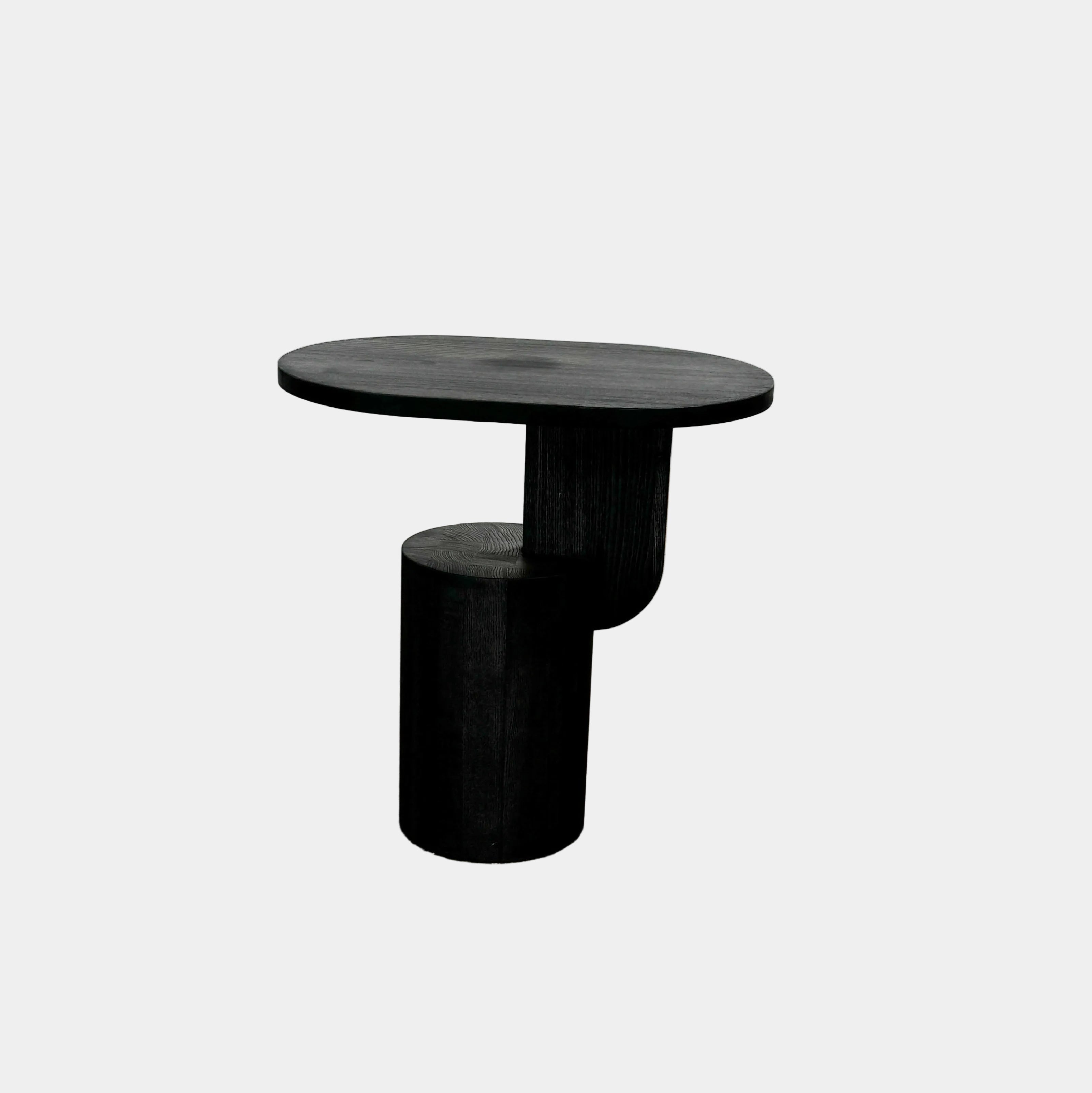 The Ferm Living Insert Side Table by Ferm Living features an oval dark wood top with a pedestal base, creating a striking accent on concrete floors and showcasing subtle Scandinavian design.