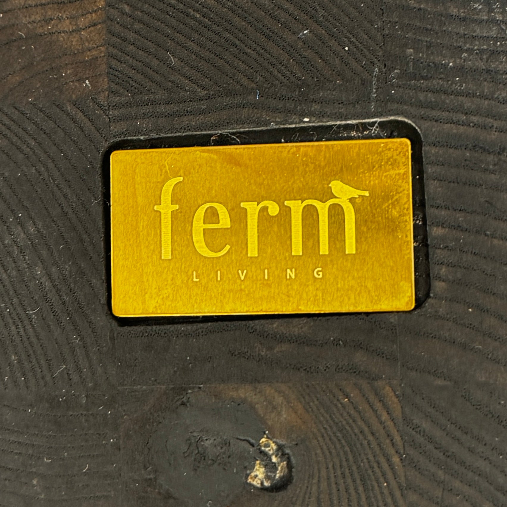 The Ferm Living Insert Side Table by Ferm Living features an oval dark wood top with a pedestal base, creating a striking accent on concrete floors and showcasing subtle Scandinavian design.