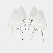The Fritz Hansen Drop Chair Set of 4 by Fritz Hansen features white modernist chairs with teardrop-shaped backs and slender metal legs, inspired by the iconic Arne Jacobsen design, arranged in a staggered formation on a plain background.