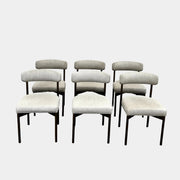 Set of six Mitchell Gold + Bob Williams Remy dining chairs with light beige upholstered seats and backs, dark wooden legs and frames, arranged in two rows against a plain light background.
