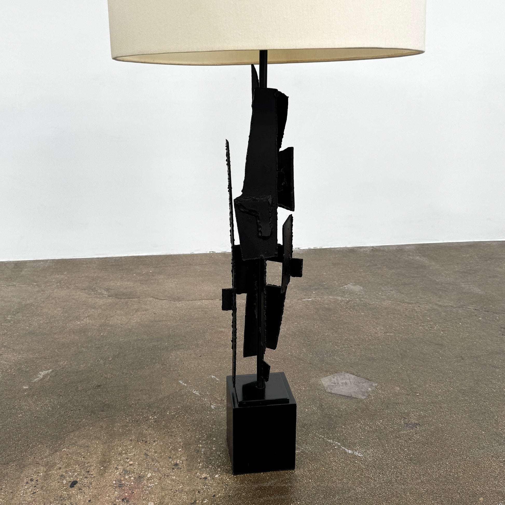A pair of Vintage Richard Barr Iron Brutalist table lamps for Laurel Lamp Co., featuring abstract black metal bases and cylindrical white shades, set against a plain white background.