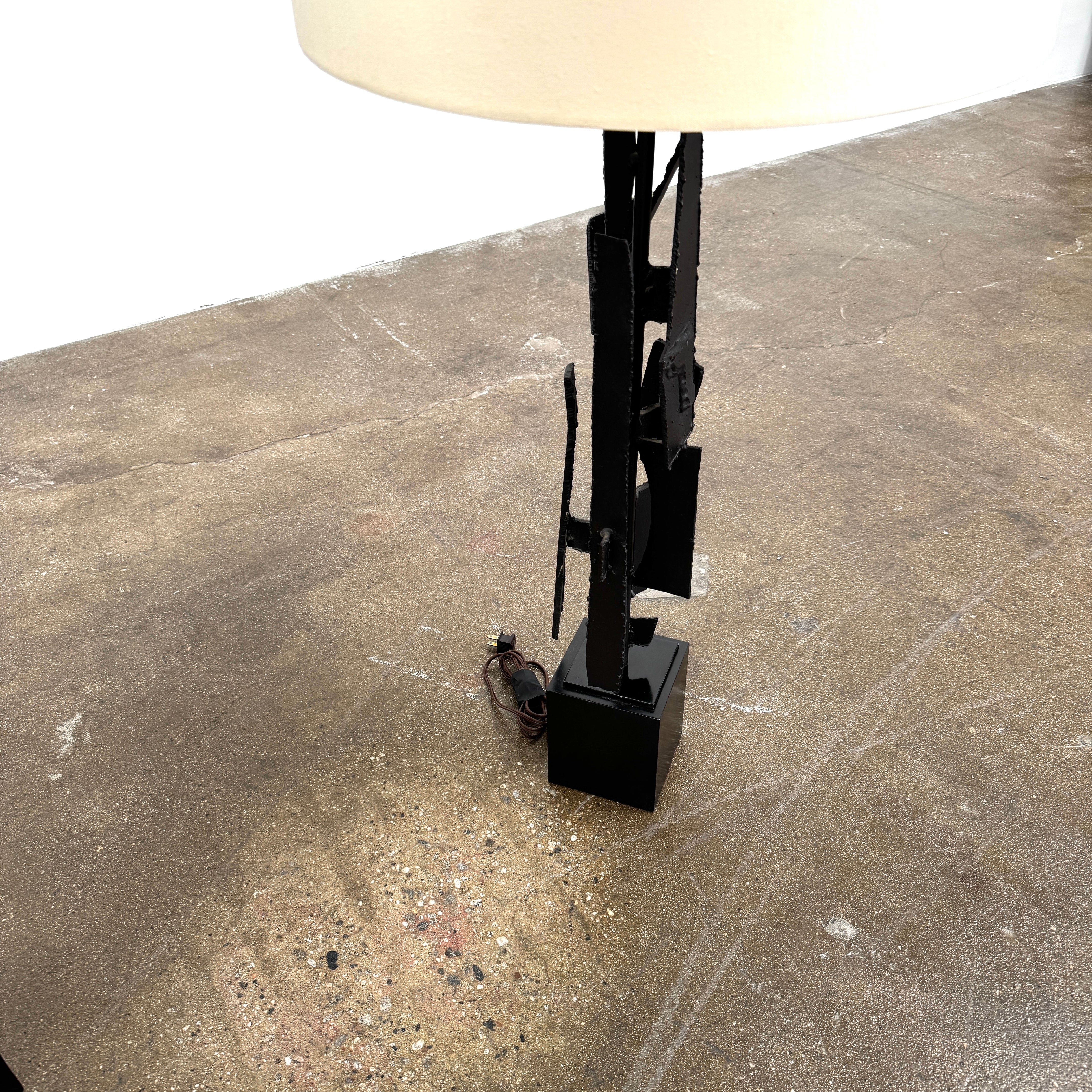 A pair of Vintage Richard Barr Iron Brutalist table lamps for Laurel Lamp Co., featuring abstract black metal bases and cylindrical white shades, set against a plain white background.