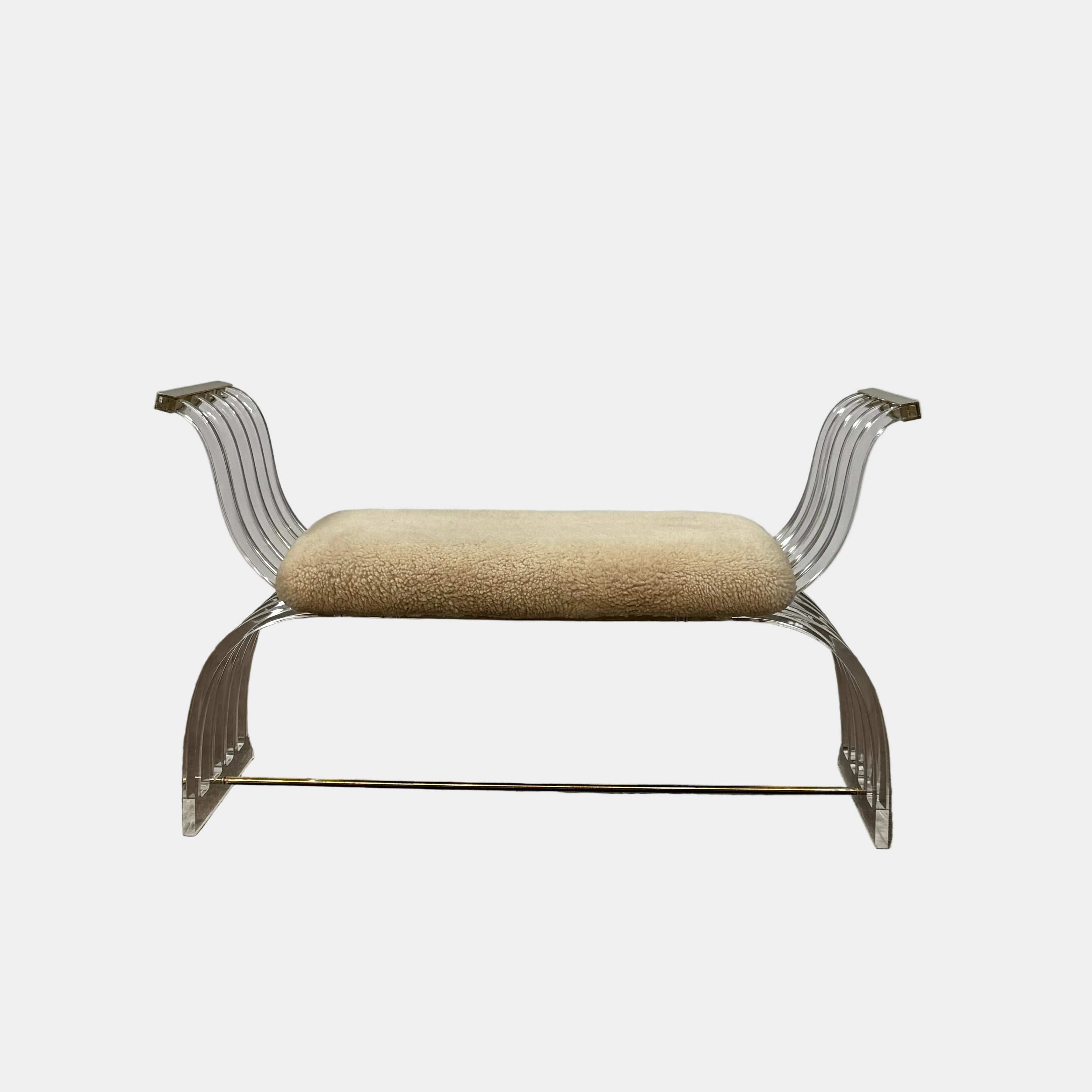 The Vintage Charles Hollis Jones Lucite Bench features a transparent acrylic frame, curved armrests, and a rectangular beige shearling cushion, shown against a plain white background.