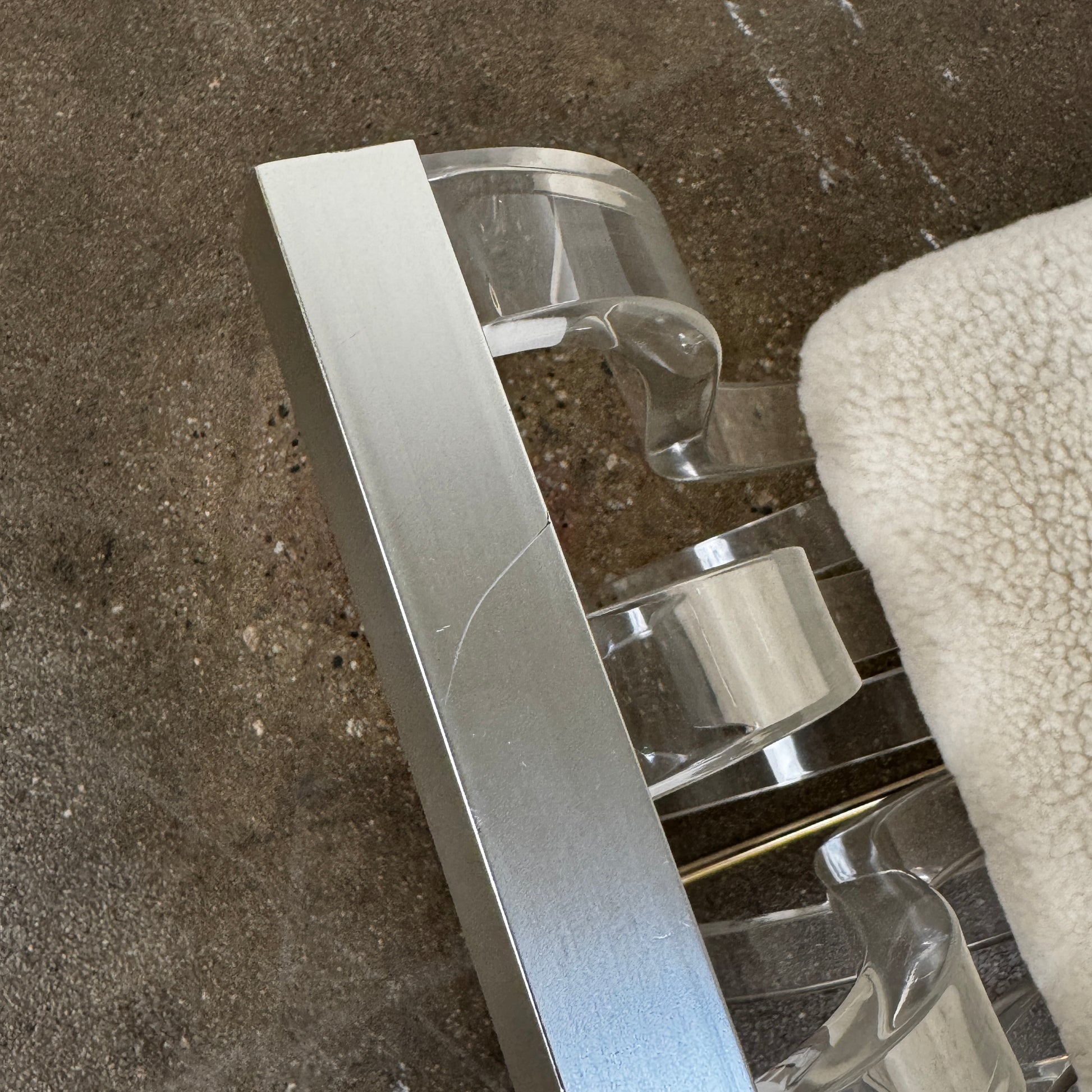 The Vintage Charles Hollis Jones Lucite Bench features a transparent acrylic frame, curved armrests, and a rectangular beige shearling cushion, shown against a plain white background.