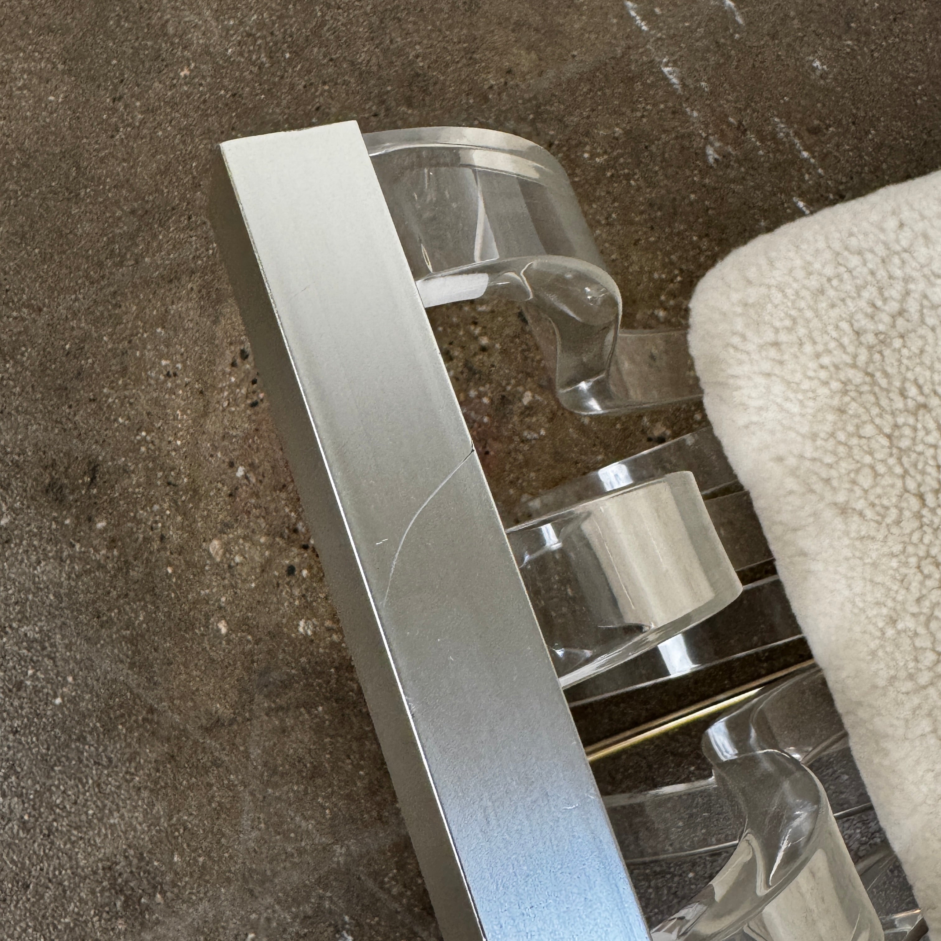 The Vintage Charles Hollis Jones Lucite Bench features a transparent acrylic frame, curved armrests, and a rectangular beige shearling cushion, shown against a plain white background.