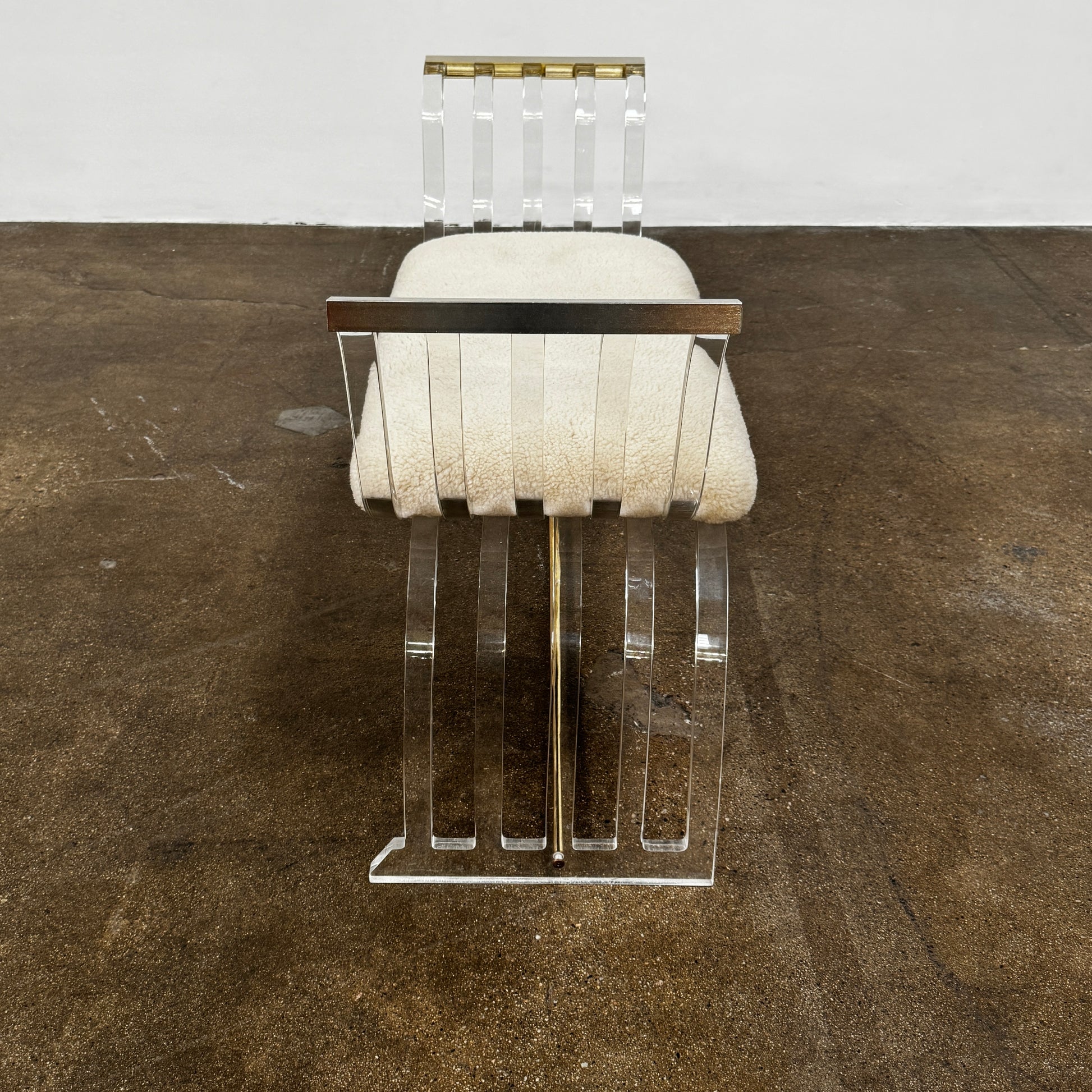The Vintage Charles Hollis Jones Lucite Bench features a transparent acrylic frame, curved armrests, and a rectangular beige shearling cushion, shown against a plain white background.