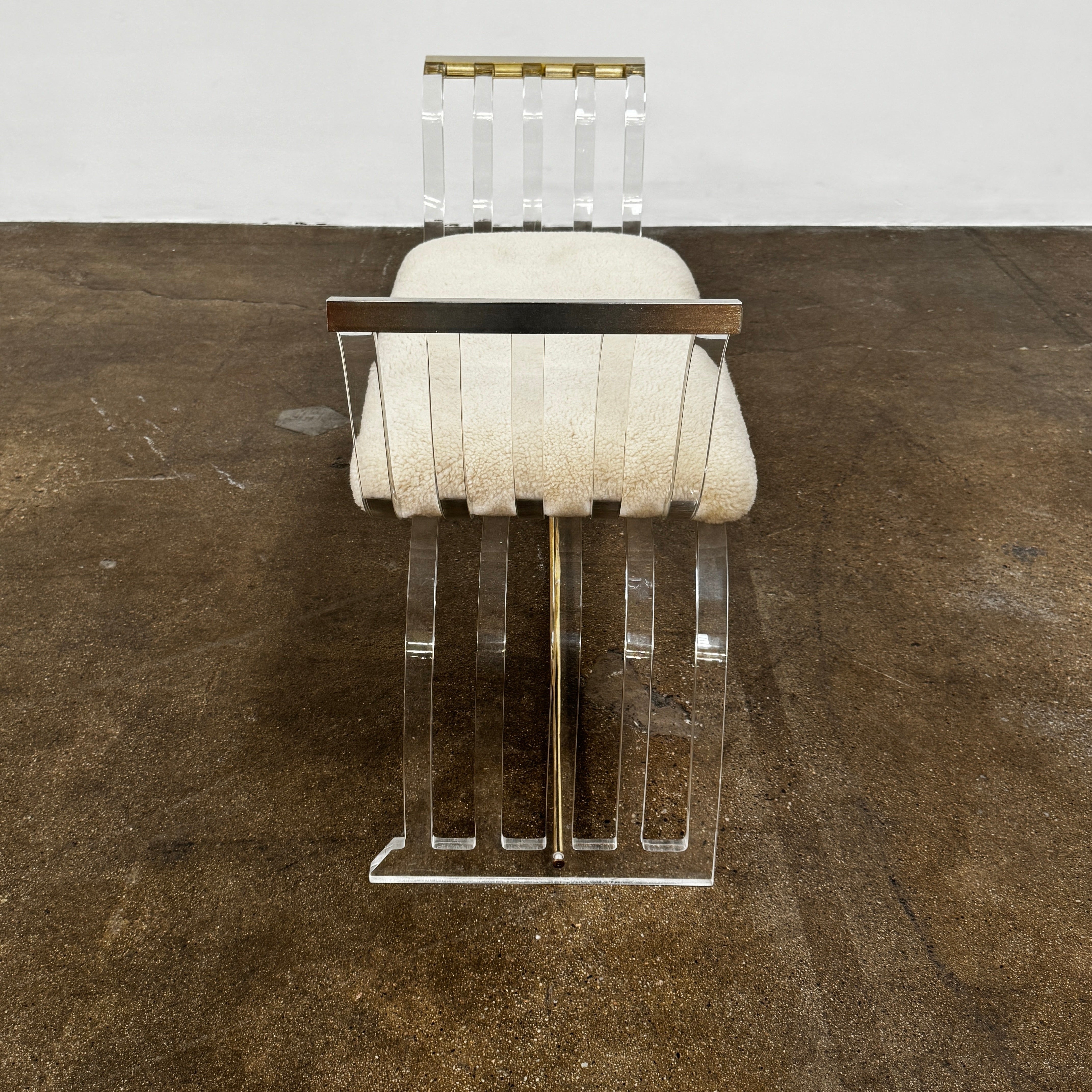 The Vintage Charles Hollis Jones Lucite Bench features a transparent acrylic frame, curved armrests, and a rectangular beige shearling cushion, shown against a plain white background.
