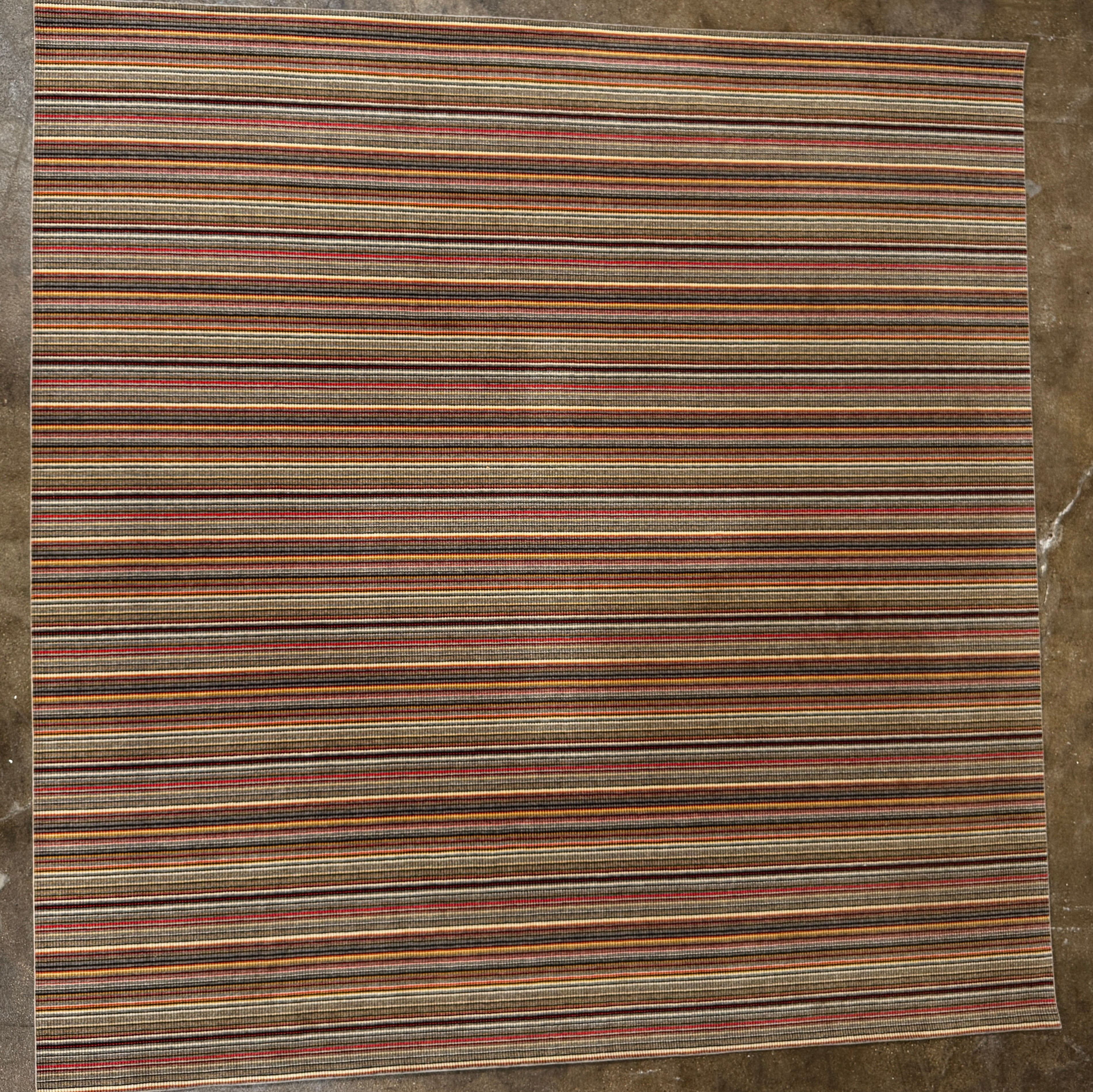 A close-up of the Maharam Interval Area Rug by Herman Miller, a modern New Zealand wool rug featuring gray, red, yellow, white, and brown stripes, shown on a white background.