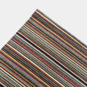A close-up of the Maharam Interval Area Rug by Herman Miller, a modern New Zealand wool rug featuring gray, red, yellow, white, and brown stripes, shown on a white background.