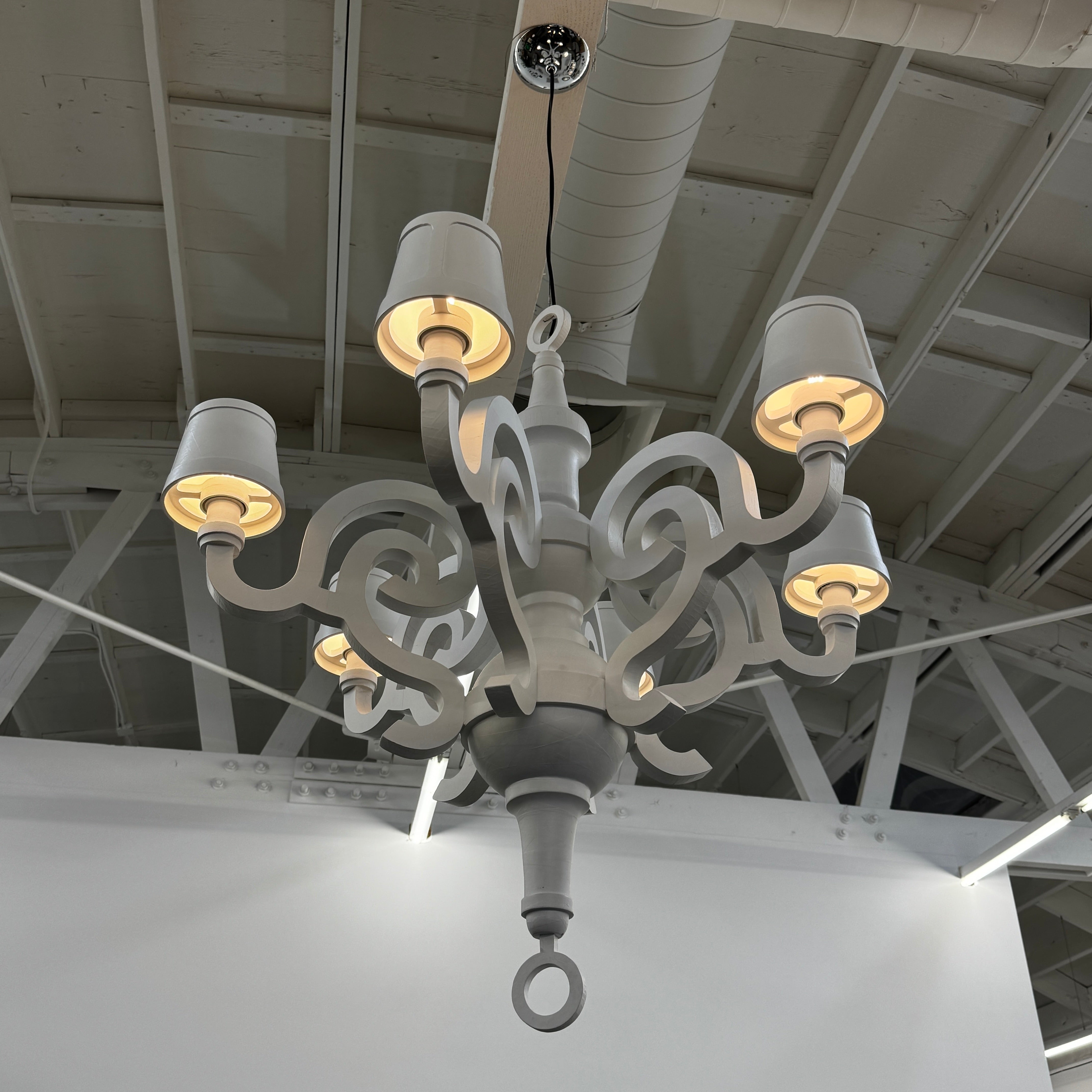 A white Moooi Paper Chandelier by Modern Resale with six arms and lampshades hangs from the ceiling on a black cord, serving as a striking 6 Light Chandelier centerpiece against a plain background.