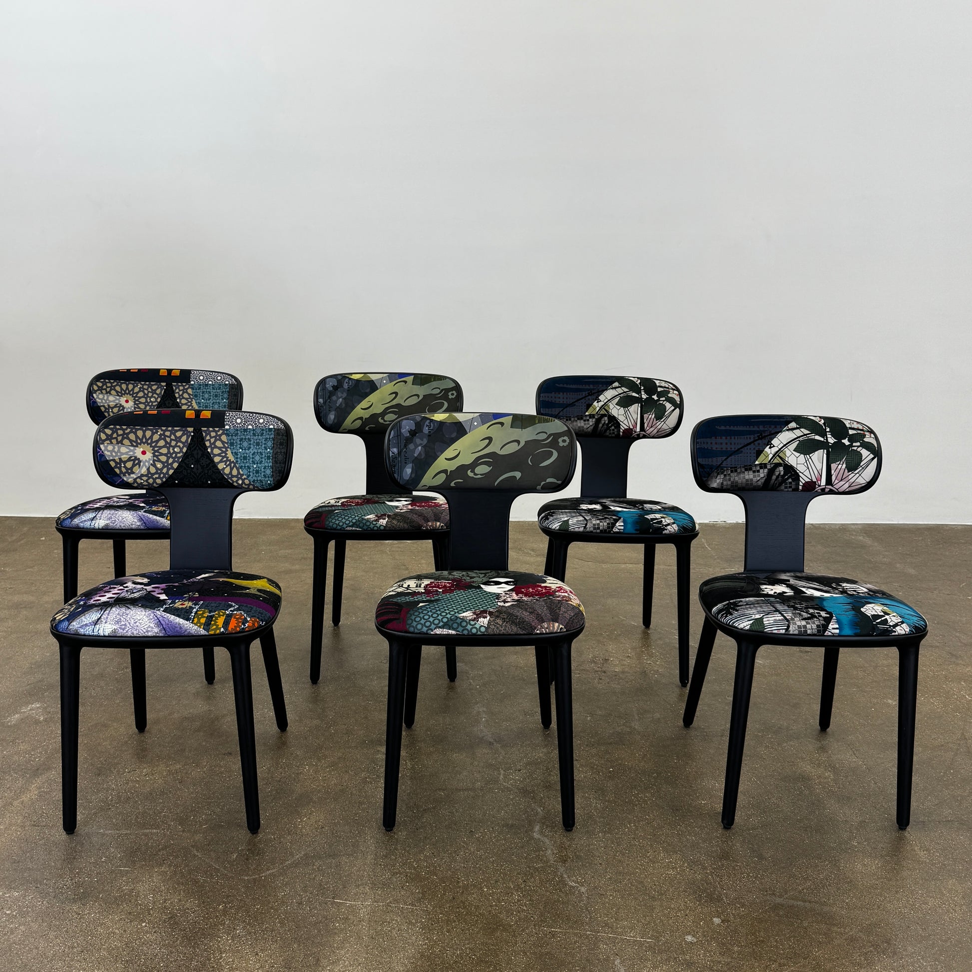 A set of six black Roche Bobois Globe Trotter Operette dining chairs, featuring patterned cushions and backs, arranged in two rows against a plain white background.