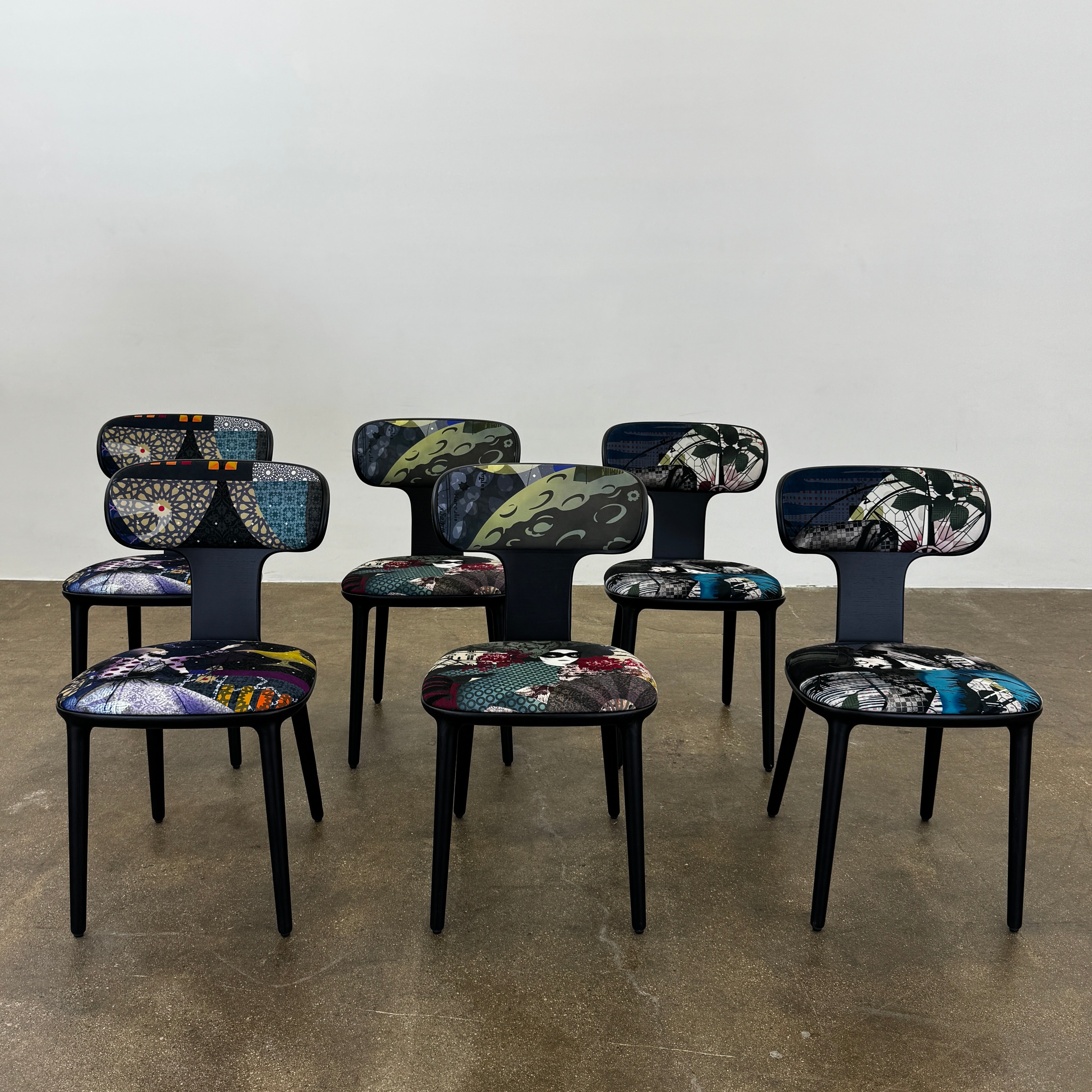 A set of six black Roche Bobois Globe Trotter Operette dining chairs, featuring patterned cushions and backs, arranged in two rows against a plain white background.