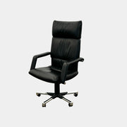 The Vitra Imago office chair by Vitra features black leather, armrests, a high backrest, and a metal five-wheel base, shown here on a concrete floor with a white background.