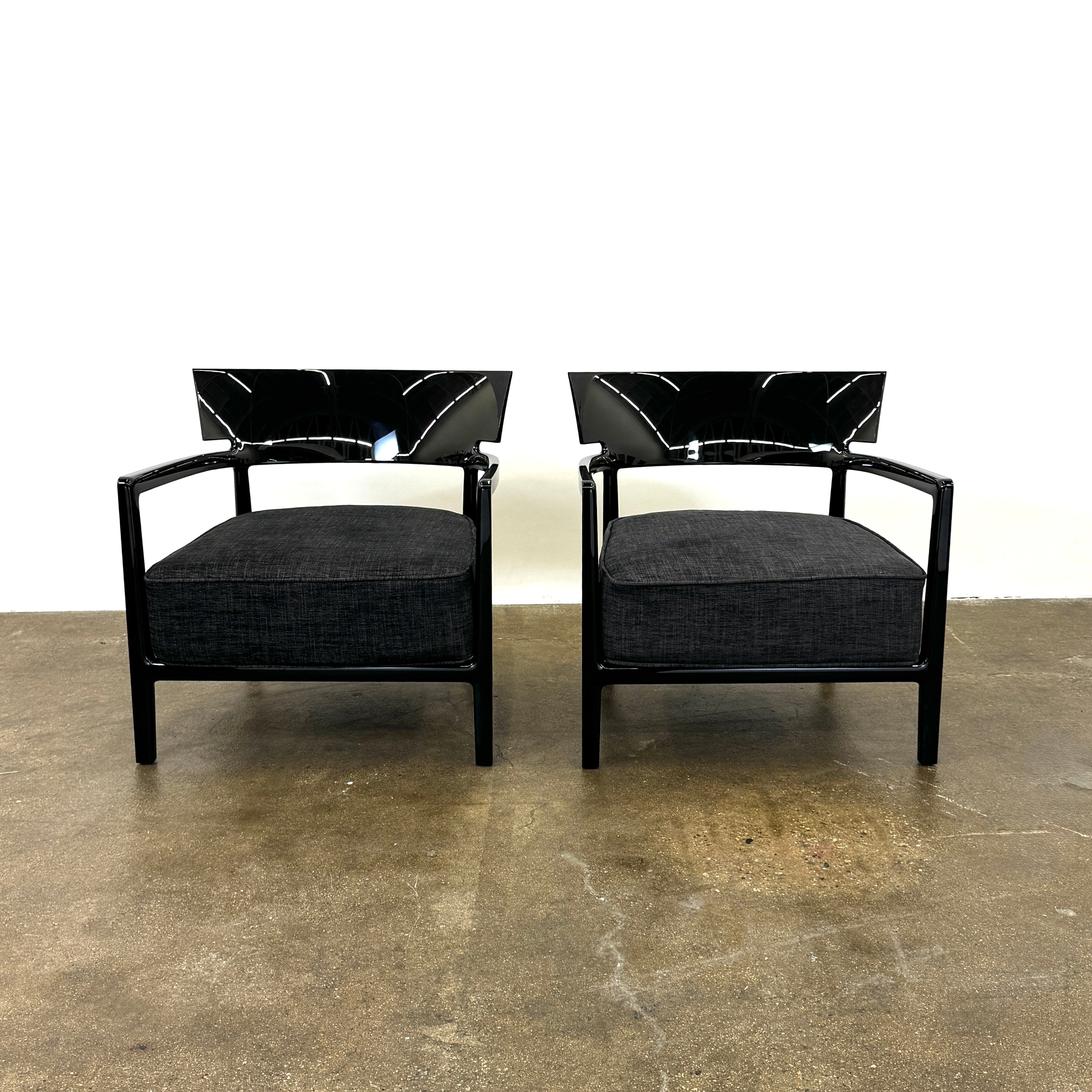 A Kartell Cara Lounge Chair by Kartell, featuring a wide black backrest and dark cushion, rests on a concrete floor in front of a plain white wall.