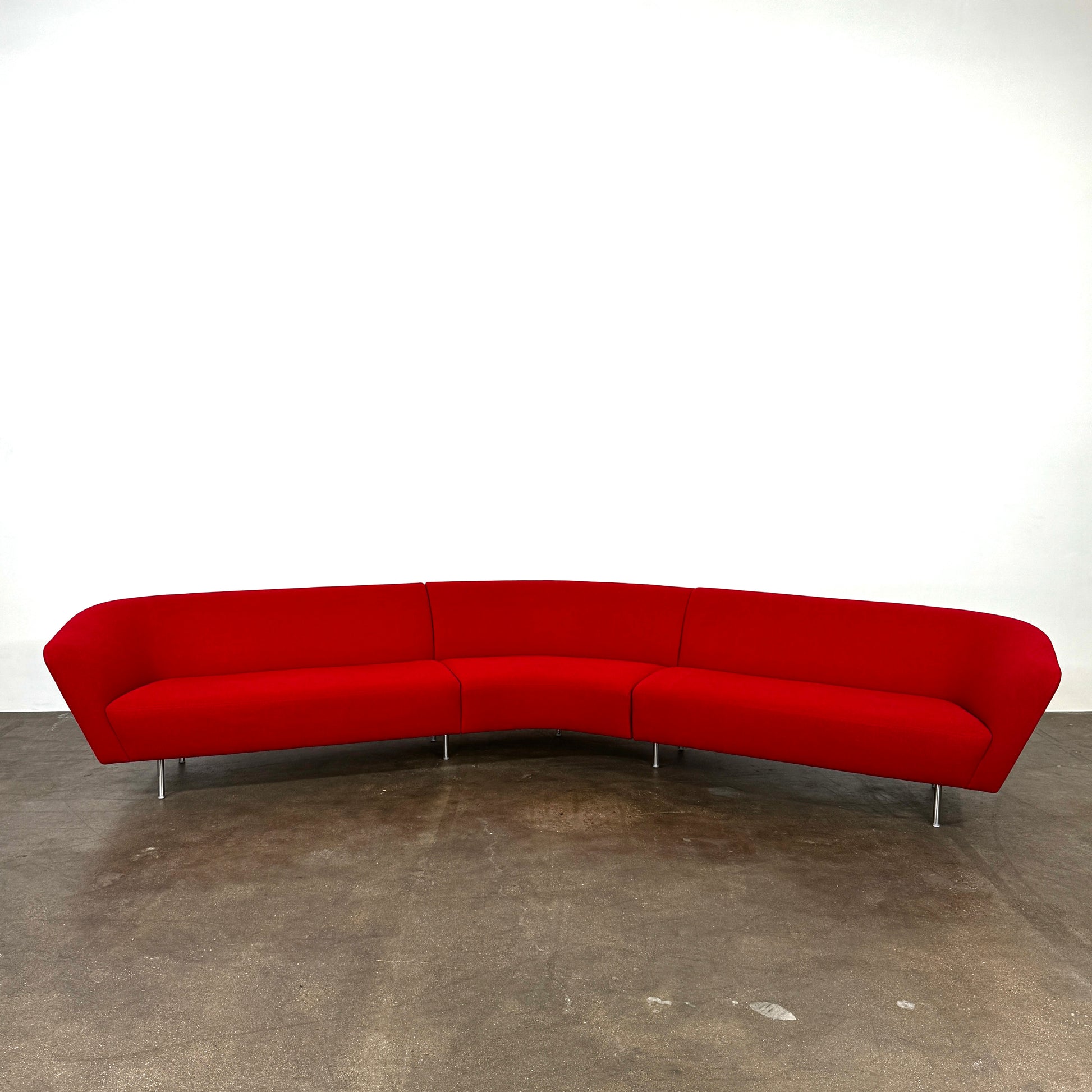 The Arper Loop Modular Sofa by Arper features a modern curved design with a geometric profile and metal legs, shown at an angle against a plain white background.