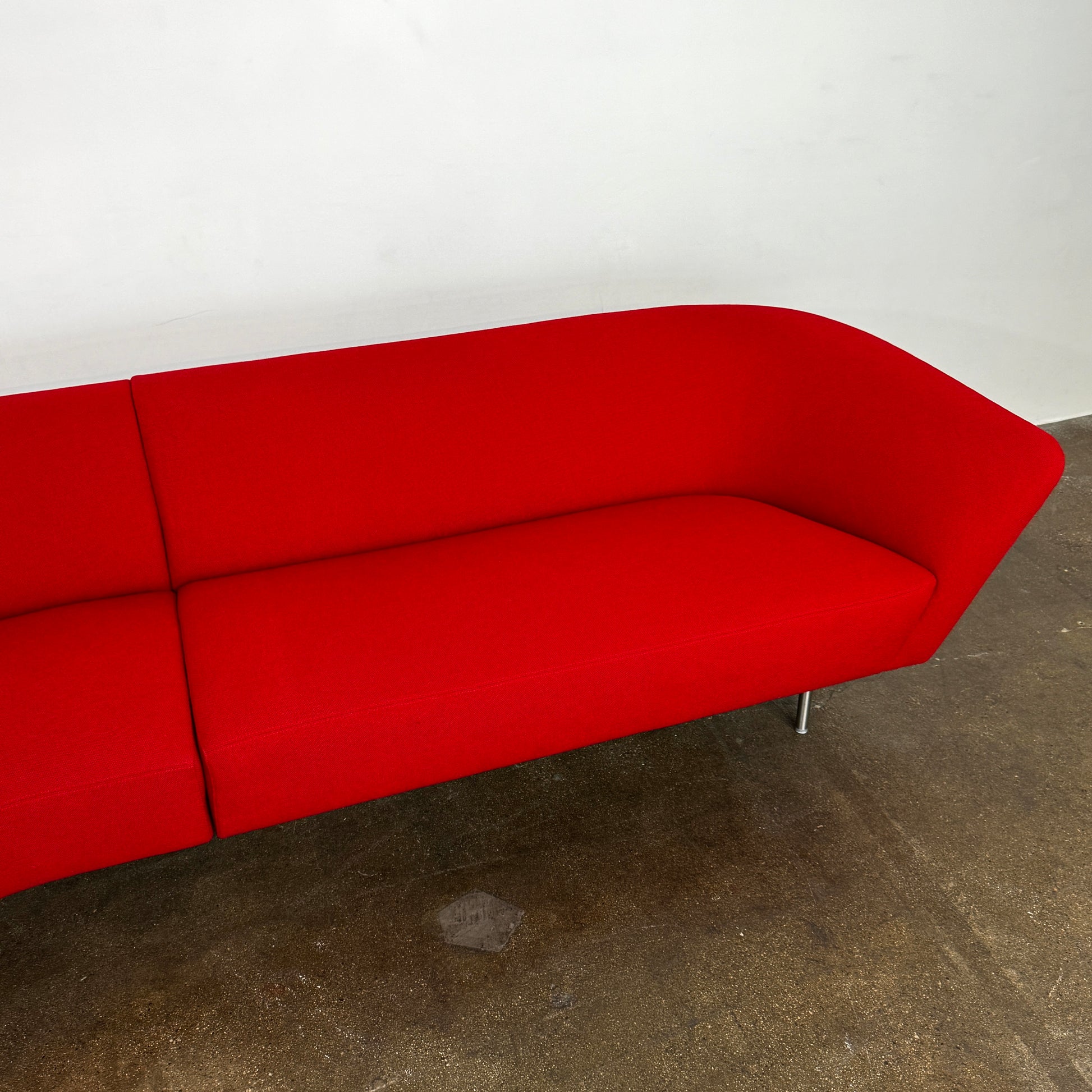 The Arper Loop Modular Sofa by Arper features a modern curved design with a geometric profile and metal legs, shown at an angle against a plain white background.