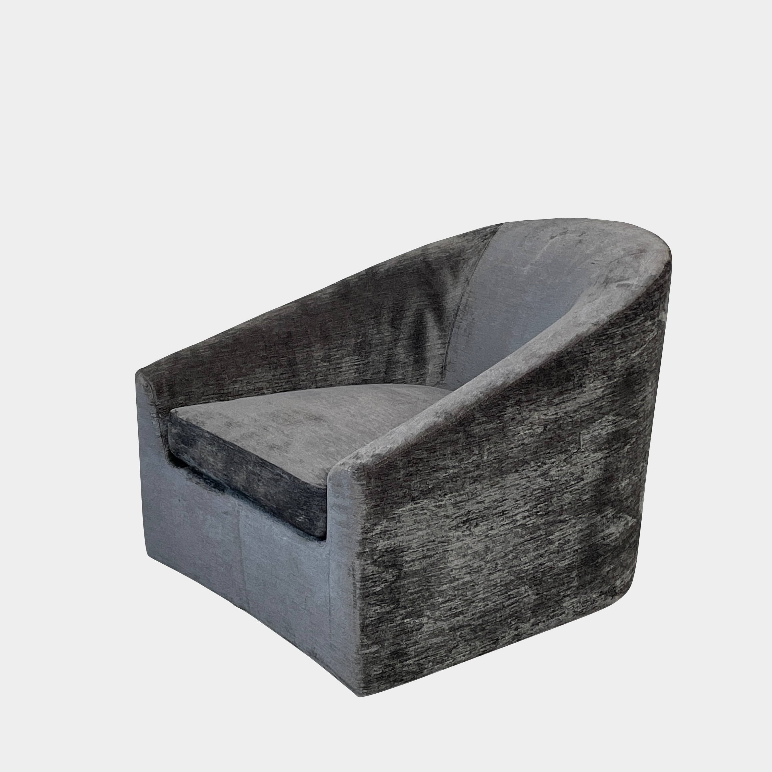 The Minotti Quinn Swivel Lounge Chair Set of 2 showcases a minimalist design with dark gray, curved forms in luxurious chenille. Ideal for the living room, these modern chairs stand out against a light gray backdrop.