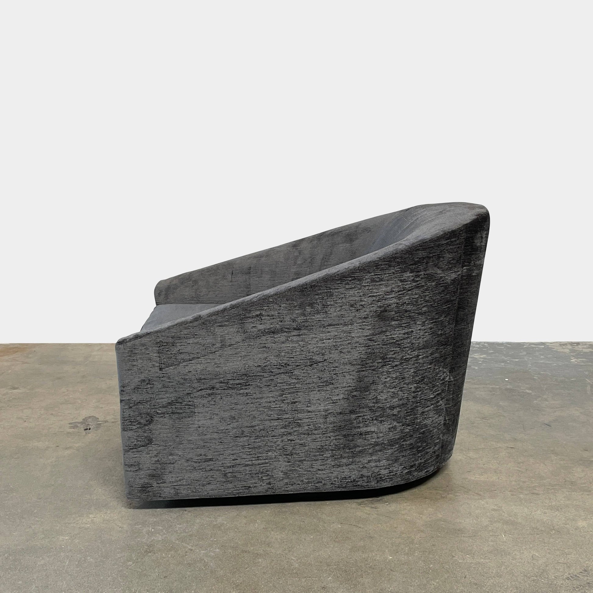 The Minotti Quinn Swivel Lounge Chair Set of 2 showcases a minimalist design with dark gray, curved forms in luxurious chenille. Ideal for the living room, these modern chairs stand out against a light gray backdrop.