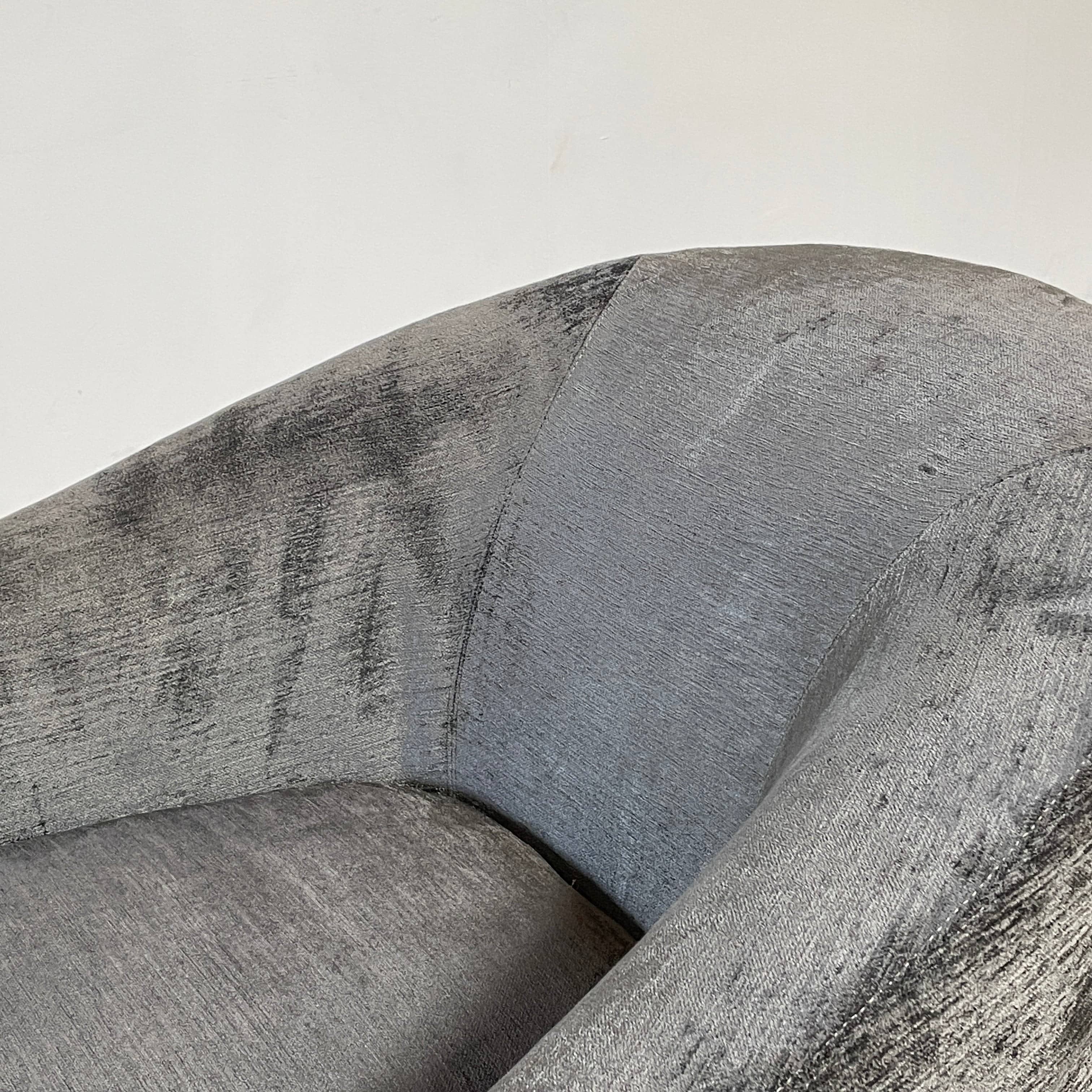 The Minotti Quinn Swivel Lounge Chair Set of 2 showcases a minimalist design with dark gray, curved forms in luxurious chenille. Ideal for the living room, these modern chairs stand out against a light gray backdrop.