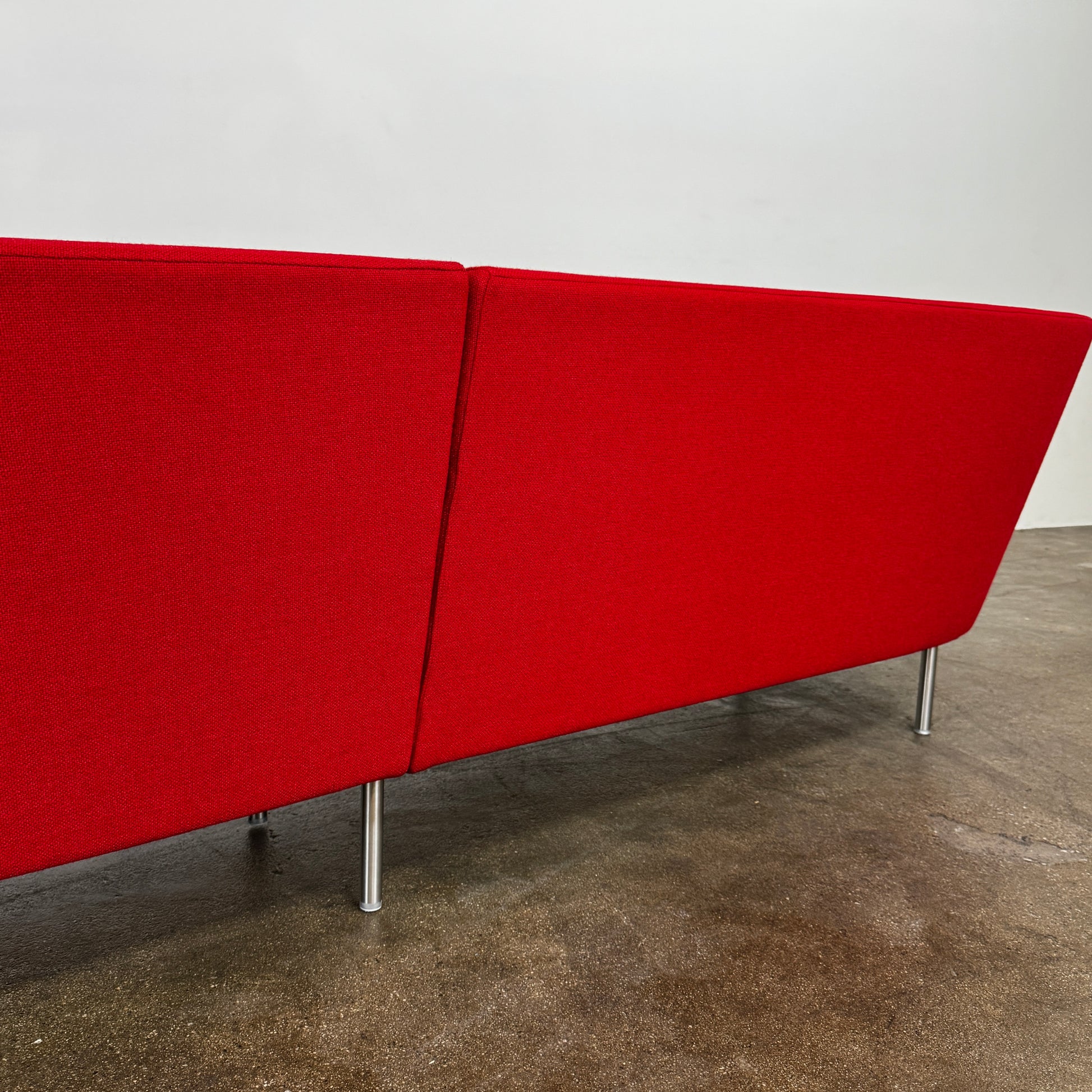 The Arper Loop Modular Sofa by Arper features a modern curved design with a geometric profile and metal legs, shown at an angle against a plain white background.