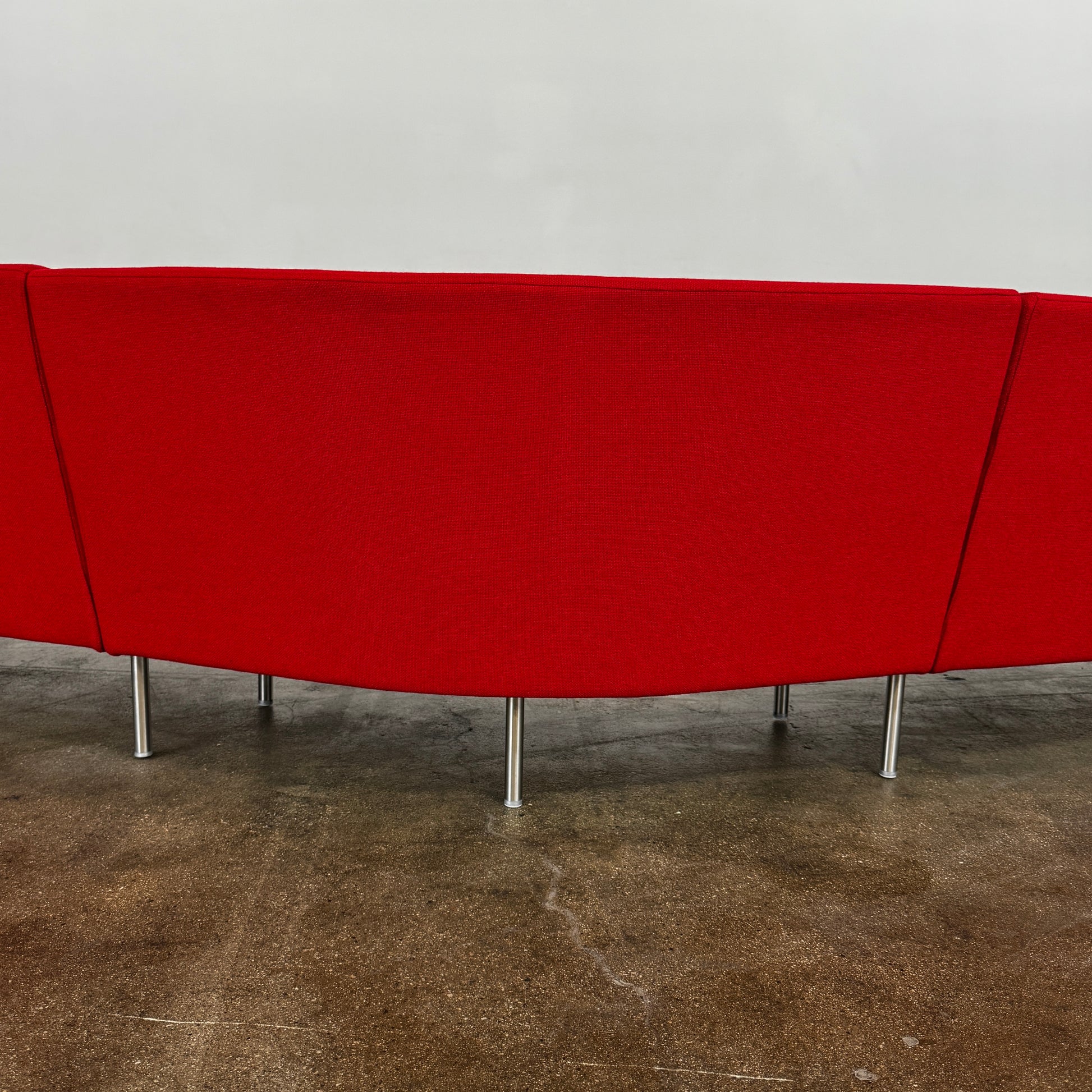 The Arper Loop Modular Sofa by Arper features a modern curved design with a geometric profile and metal legs, shown at an angle against a plain white background.