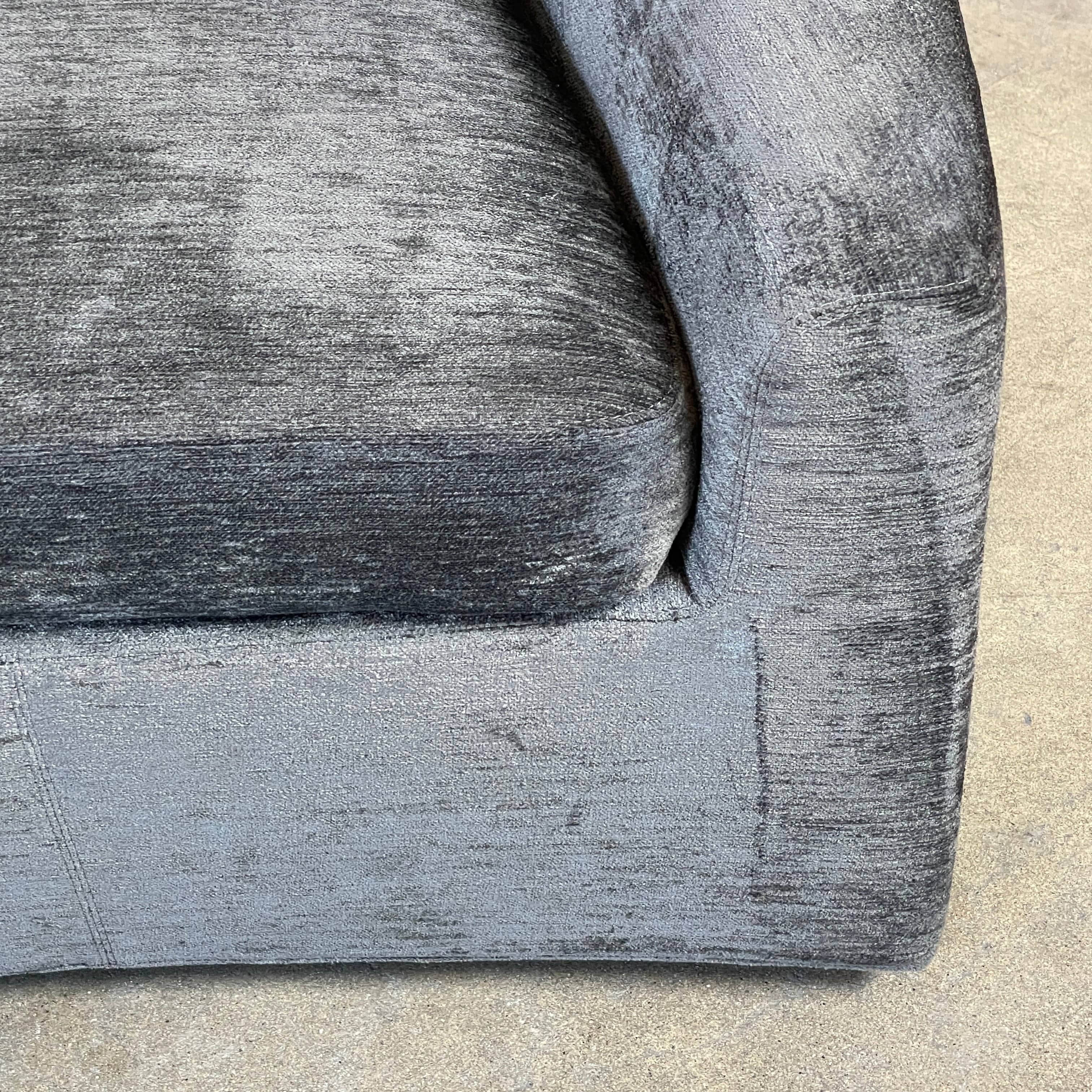 The Minotti Quinn Swivel Lounge Chair Set of 2 showcases a minimalist design with dark gray, curved forms in luxurious chenille. Ideal for the living room, these modern chairs stand out against a light gray backdrop.