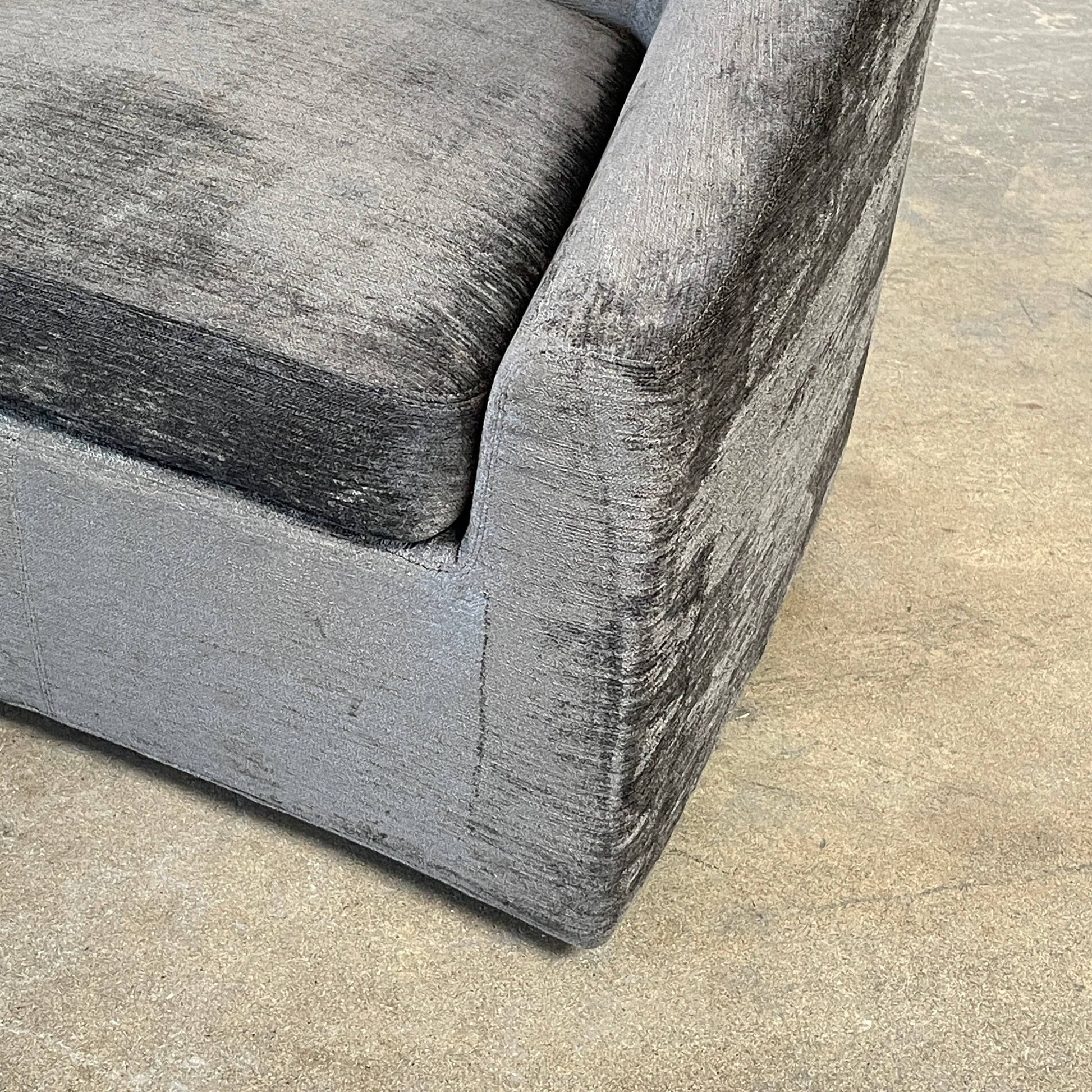 The Minotti Quinn Swivel Lounge Chair Set of 2 showcases a minimalist design with dark gray, curved forms in luxurious chenille. Ideal for the living room, these modern chairs stand out against a light gray backdrop.