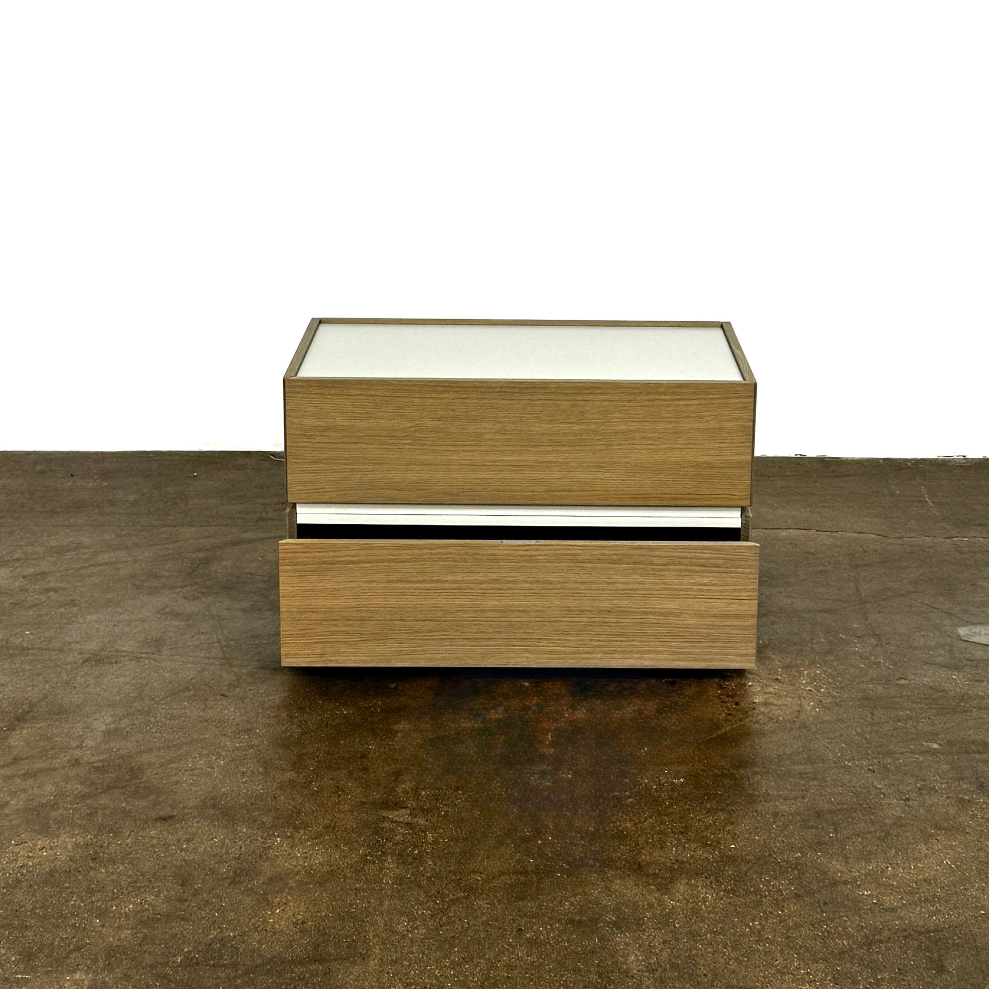 The Sangiacomo Cidori Small Chest of Drawers by Sangiacomo is ideal for contemporary spaces, featuring a light-toned top and single partially open drawer, set on a concrete floor against a white wall.