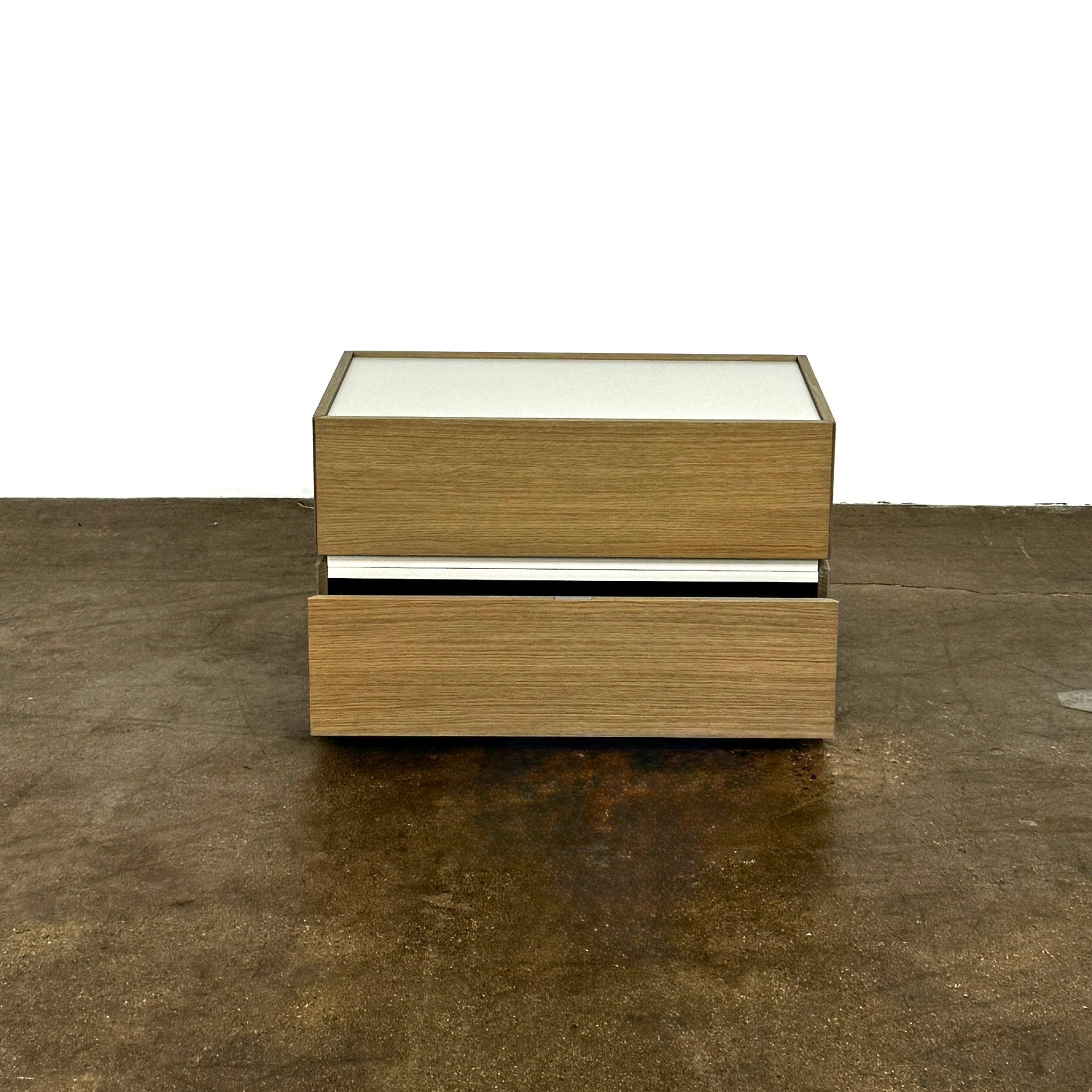 The Sangiacomo Cidori Small Chest of Drawers by Sangiacomo is ideal for contemporary spaces, featuring a light-toned top and single partially open drawer, set on a concrete floor against a white wall.