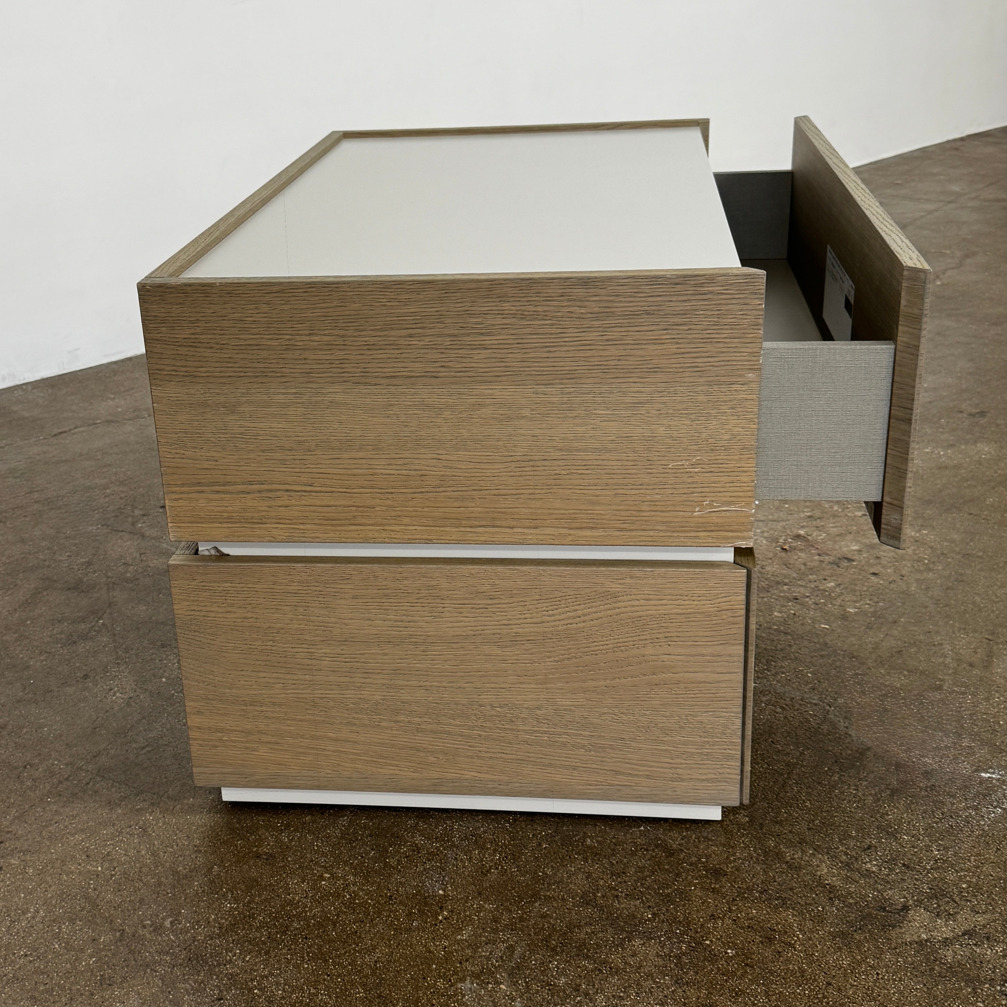 The Sangiacomo Cidori Small Chest of Drawers by Sangiacomo is ideal for contemporary spaces, featuring a light-toned top and single partially open drawer, set on a concrete floor against a white wall.