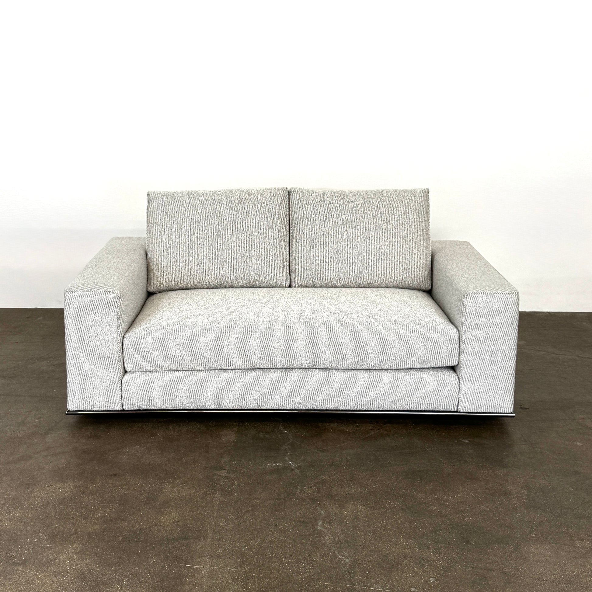 The Minotti Hamilton Love Seat 71" by Minotti, in light gray with two seat and two backrest cushions, is shown against a plain white background.