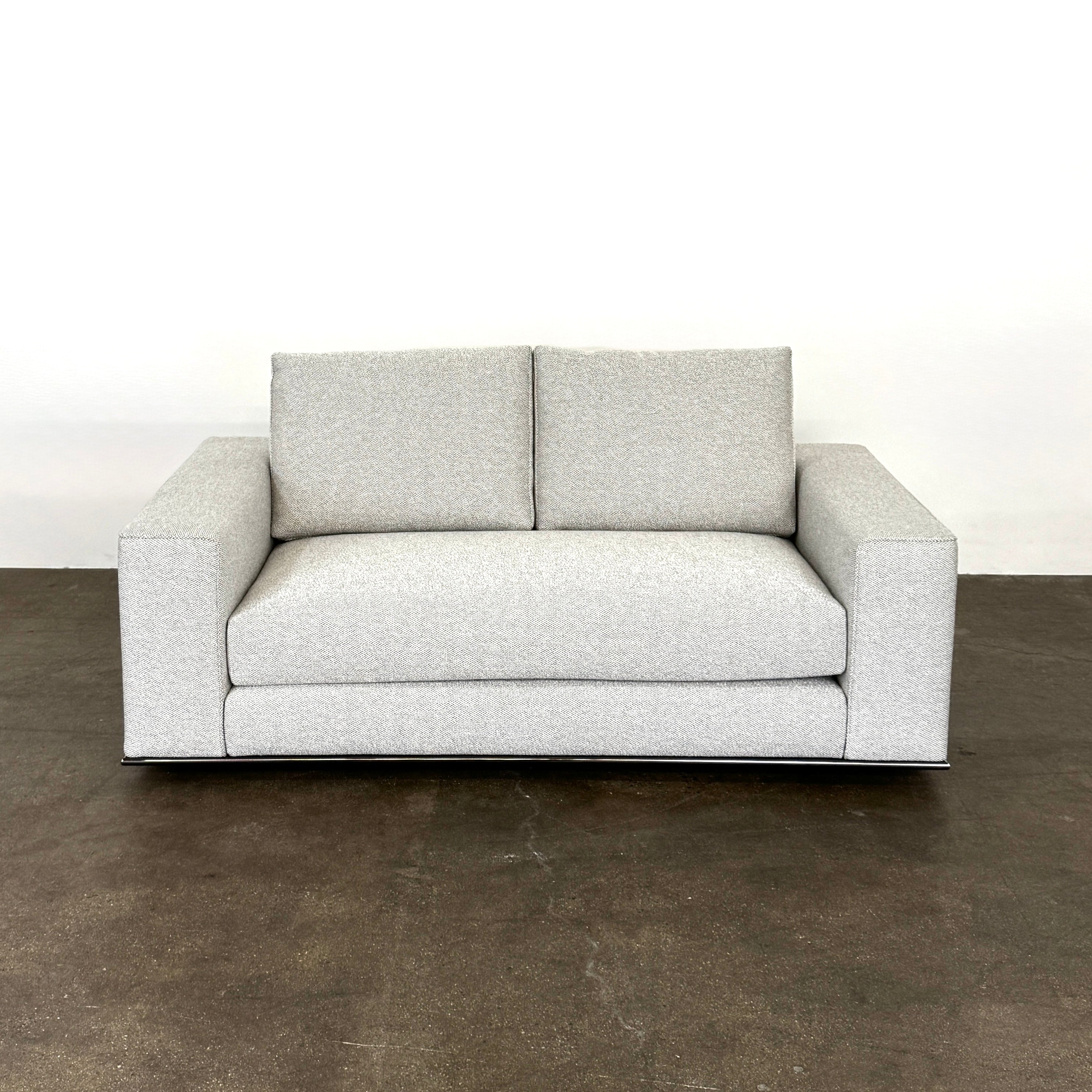 The Minotti Hamilton Love Seat 71" by Minotti, in light gray with two seat and two backrest cushions, is shown against a plain white background.