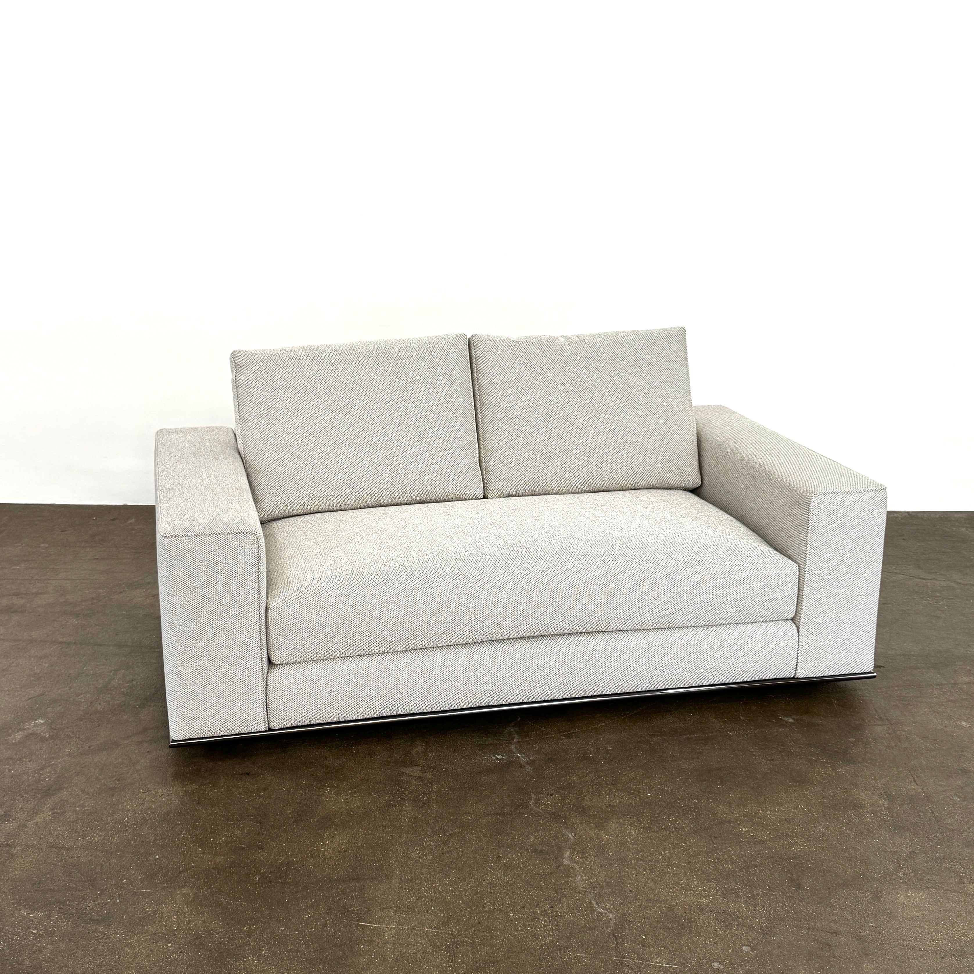 The Minotti Hamilton Love Seat 71" by Minotti, in light gray with two seat and two backrest cushions, is shown against a plain white background.