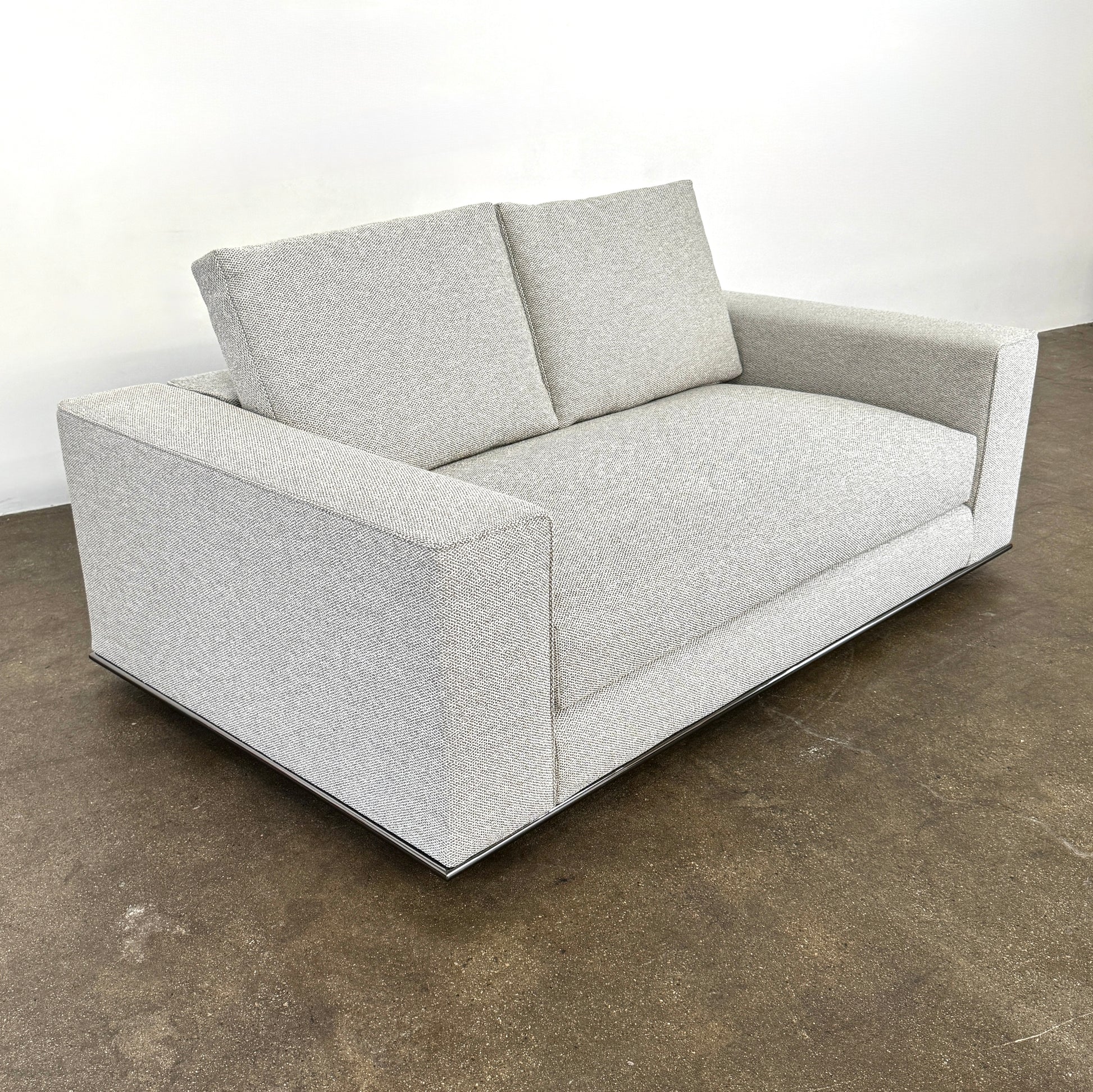 The Minotti Hamilton Love Seat 71" by Minotti, in light gray with two seat and two backrest cushions, is shown against a plain white background.
