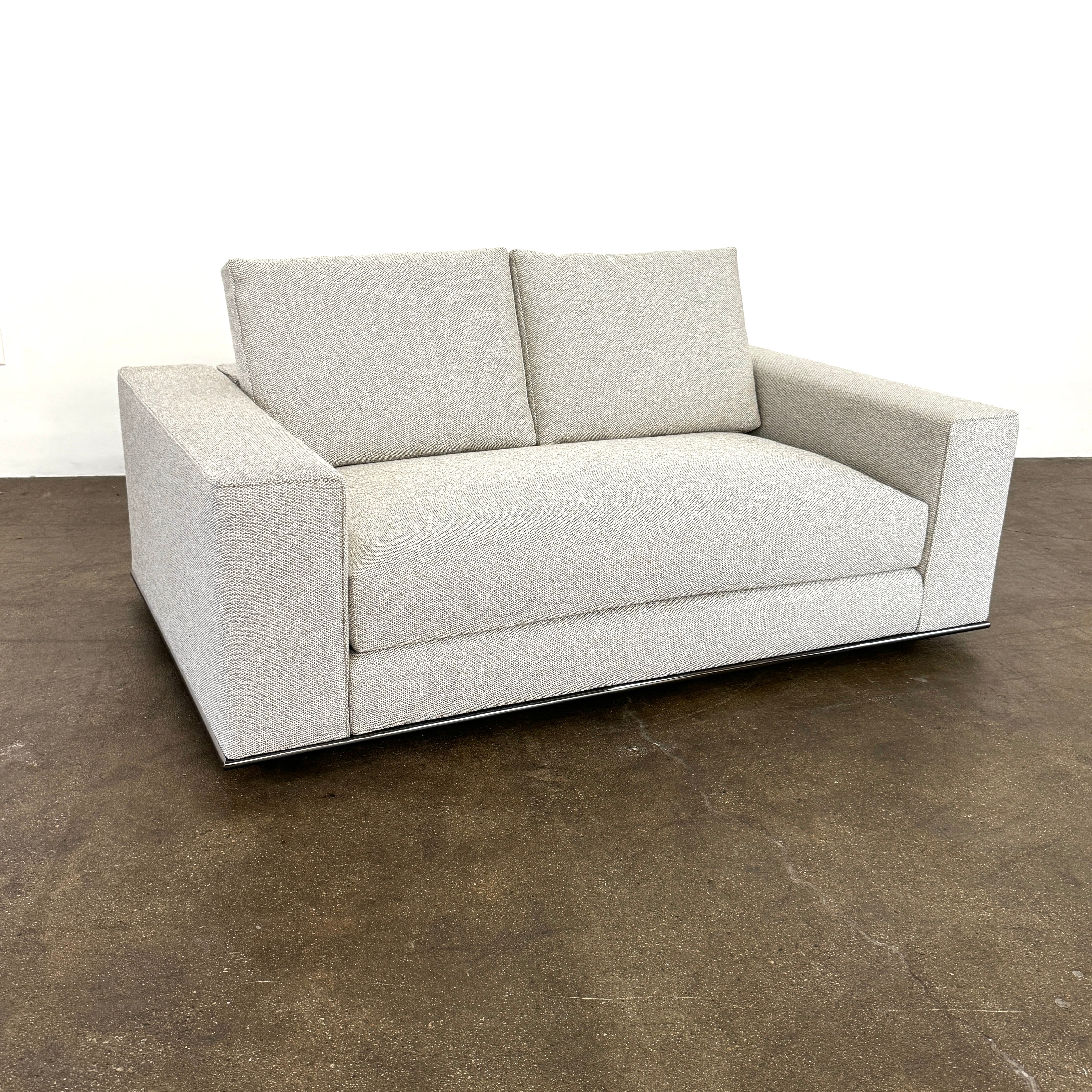 The Minotti Hamilton Love Seat 71" by Minotti, in light gray with two seat and two backrest cushions, is shown against a plain white background.