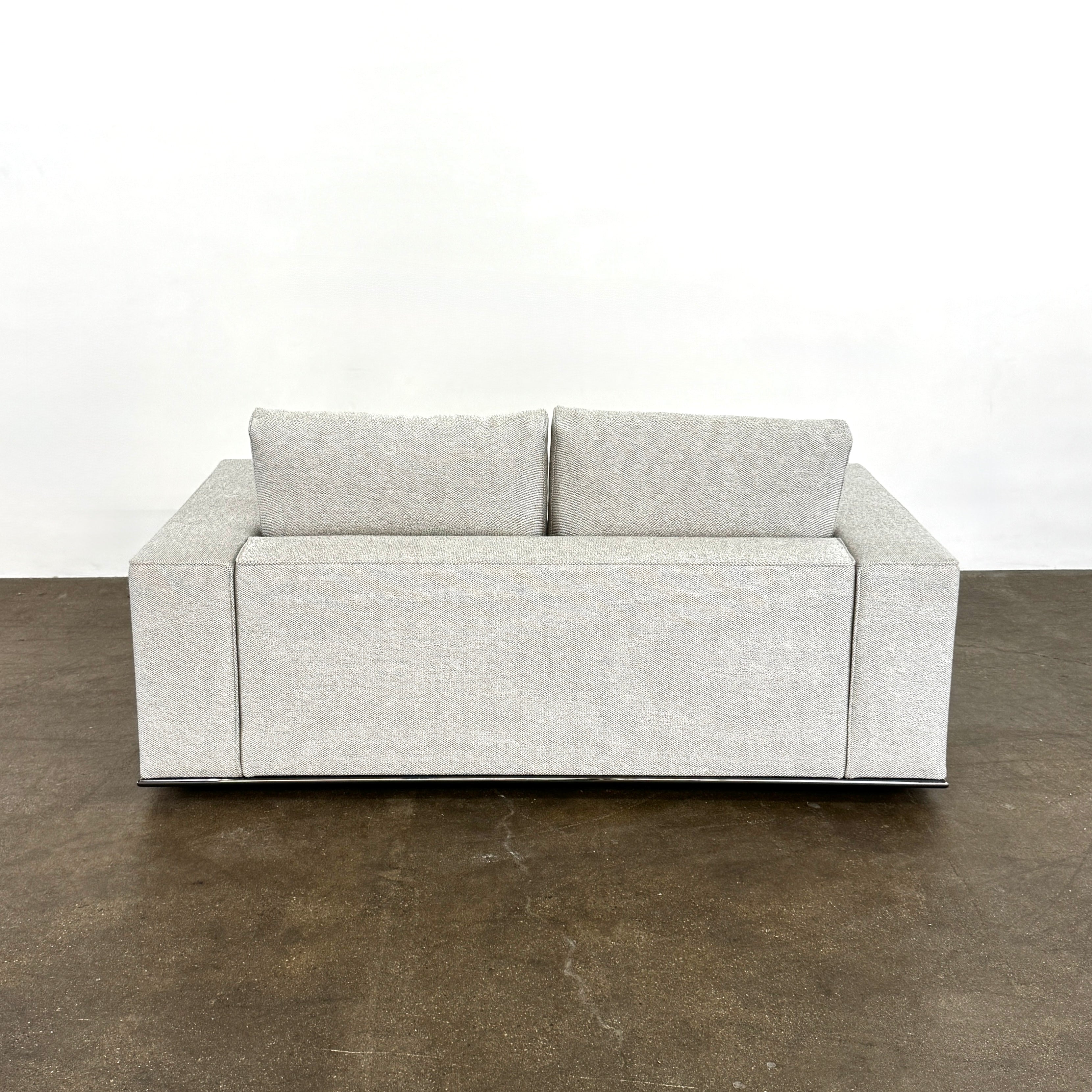 The Minotti Hamilton Love Seat 71" by Minotti, in light gray with two seat and two backrest cushions, is shown against a plain white background.