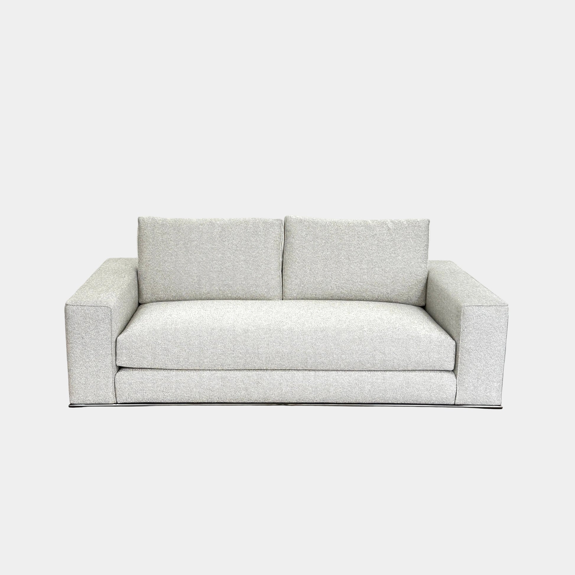 A close-up of knitted fabric featuring a Minotti label on black textile highlights the refined details of modern living furniture like the Minotti Hamilton Love Seat 82".