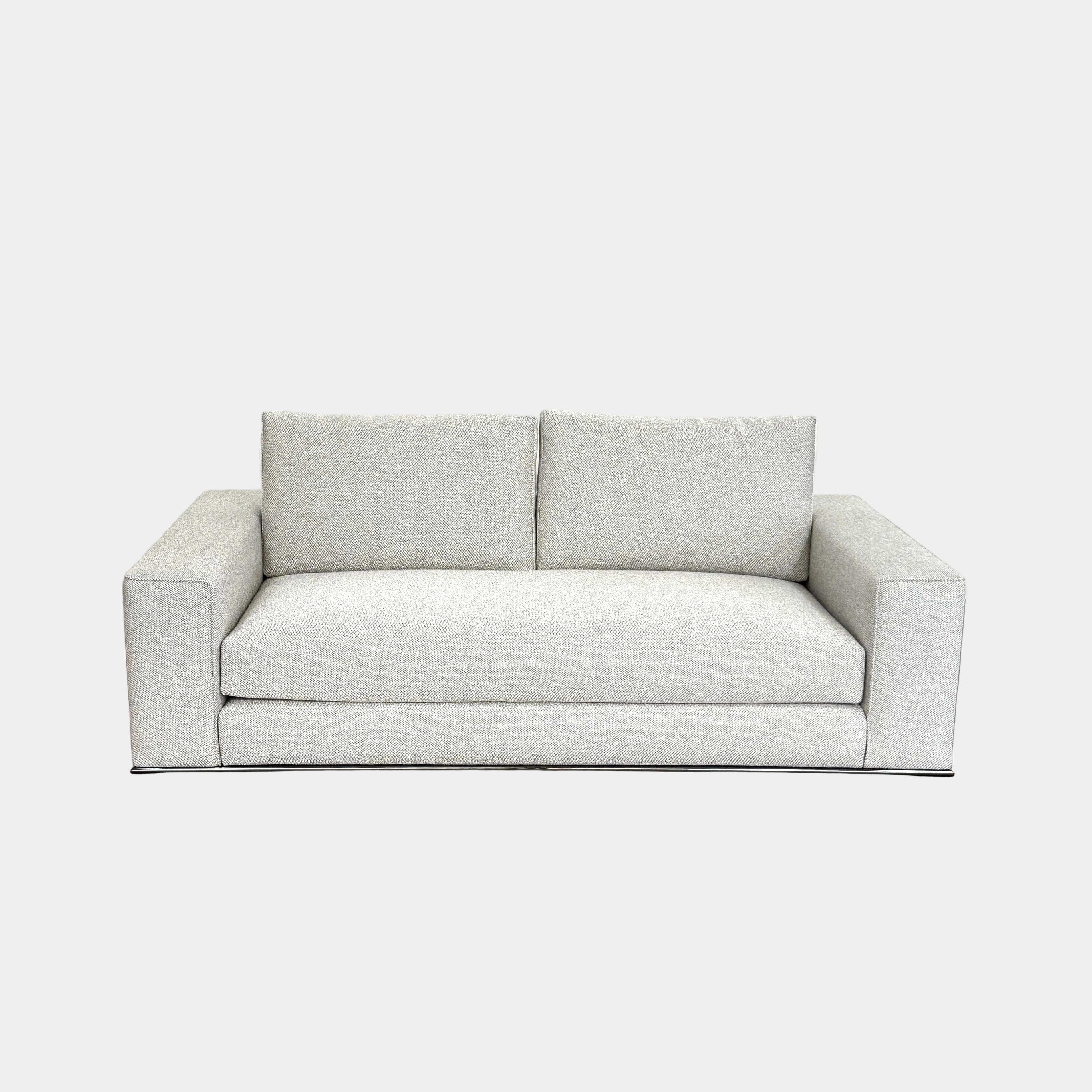 A close-up of knitted fabric featuring a Minotti label on black textile highlights the refined details of modern living furniture like the Minotti Hamilton Love Seat 82".