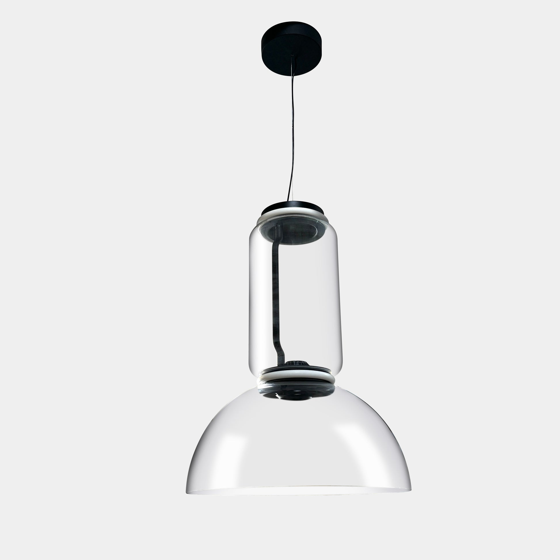 The Flos Noctambule Low Cylinder and Bowl LED Pendant 1 by Flos features a transparent blown crystal glass shade with a cylindrical glass element, suspended from the ceiling by a black cord.