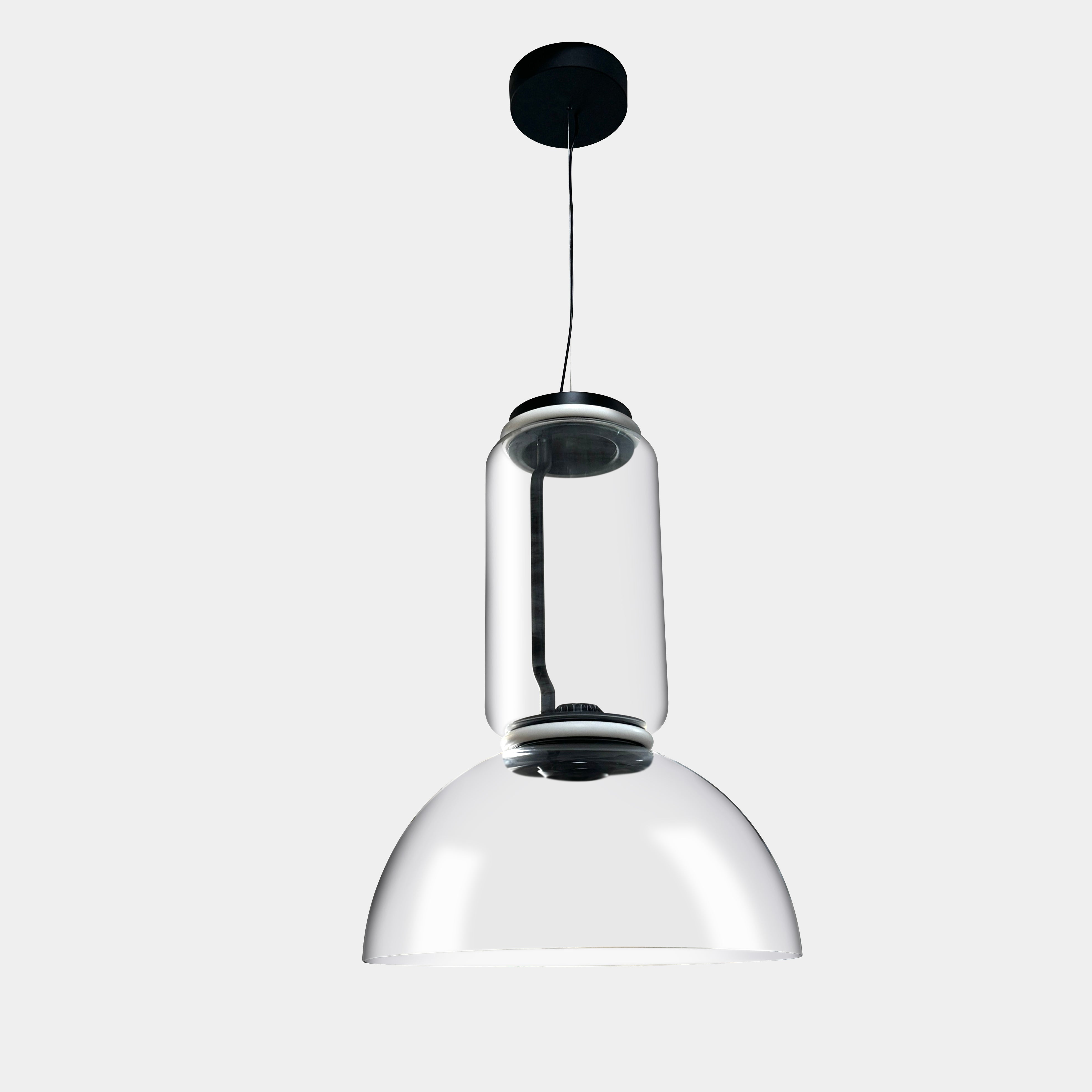 The Flos Noctambule Low Cylinder and Bowl LED Pendant 1 by Flos features a transparent blown crystal glass shade with a cylindrical glass element, suspended from the ceiling by a black cord.
