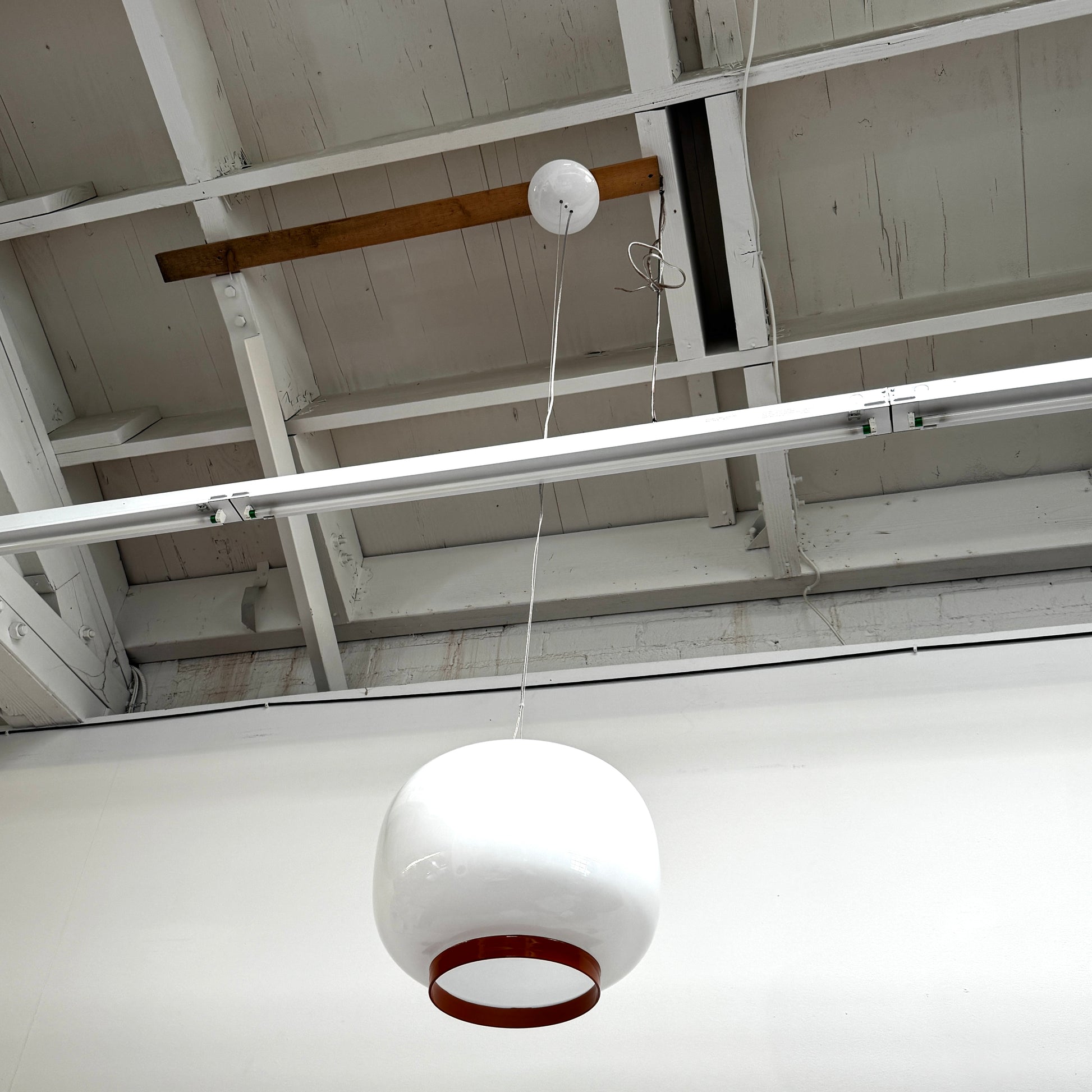 The Foscarini Chouchin 1 Pendant by Foscarini features a glossy white, rounded glass shade with a brown base, suspended on a single cable—evoking the style of a Japanese paper lantern.