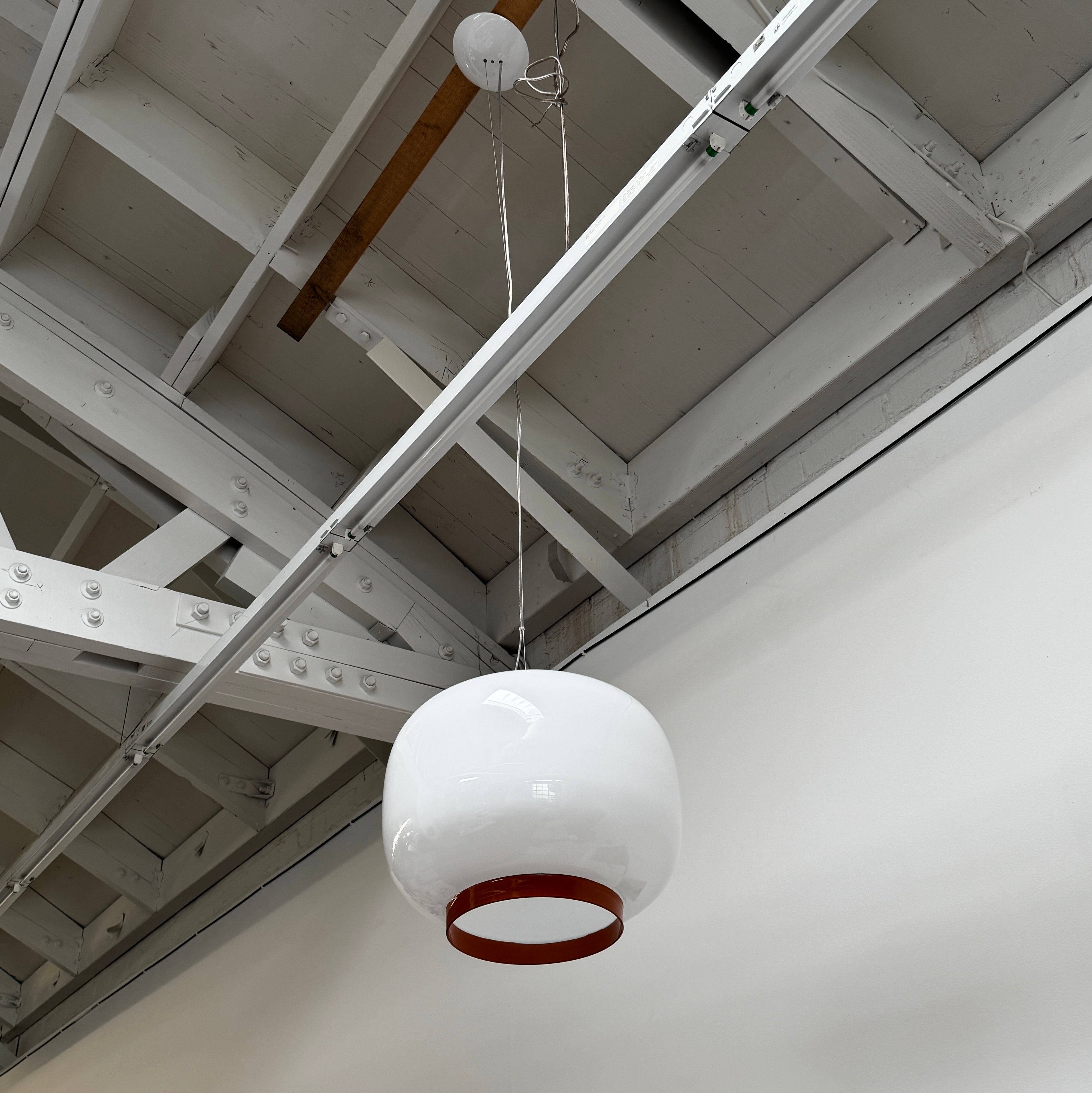 The Foscarini Chouchin 1 Pendant by Foscarini features a glossy white, rounded glass shade with a brown base, suspended on a single cable—evoking the style of a Japanese paper lantern.