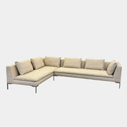 A beige B&B Italia Charles Sectional with five back cushions and metal legs sits on a concrete floor against a plain white wall.