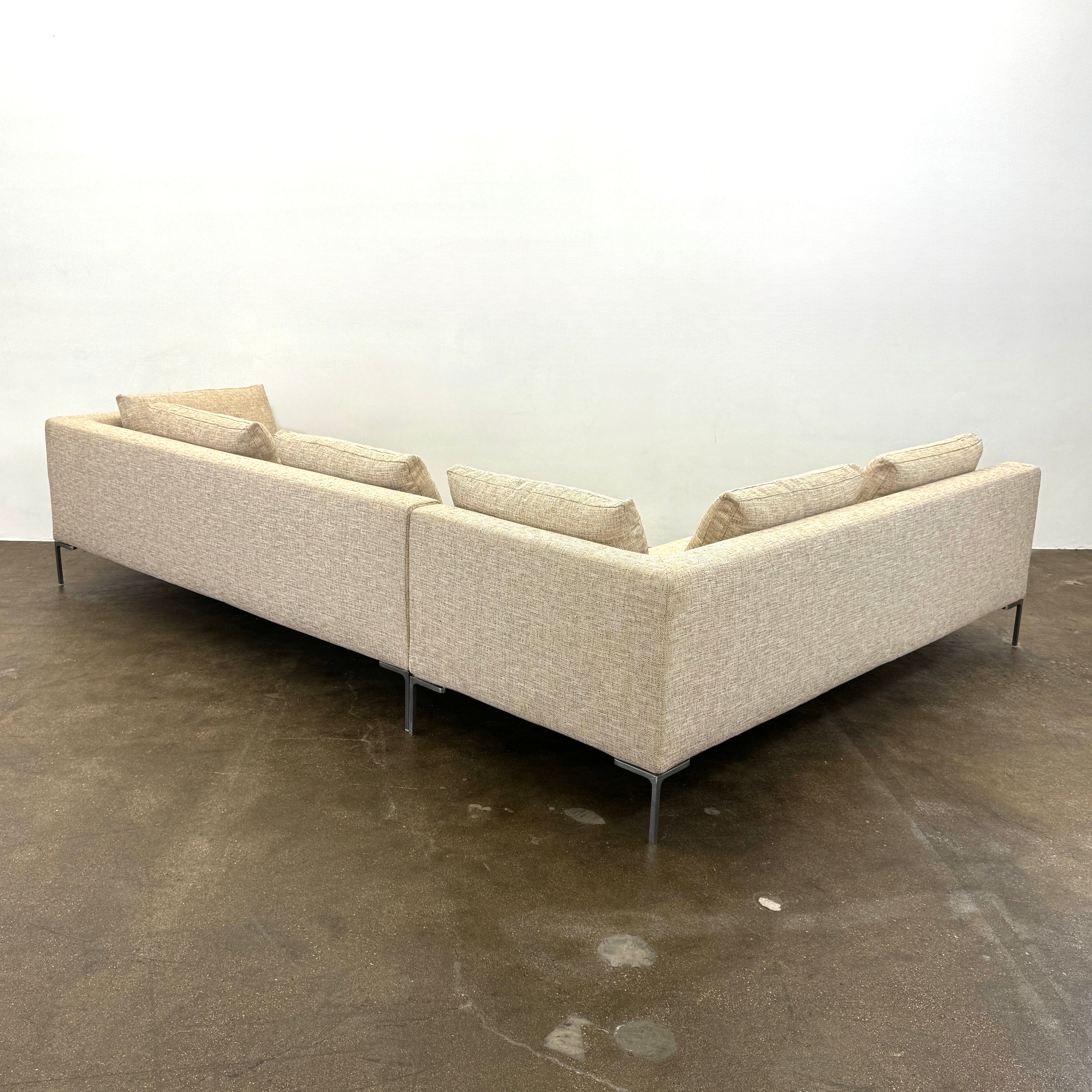 A beige B&B Italia Charles Sectional with five back cushions and metal legs sits on a concrete floor against a plain white wall.